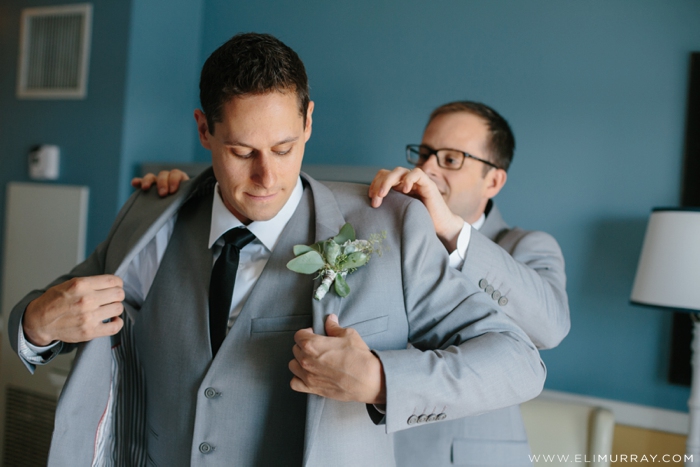 groom with groomsman getting into grey suit