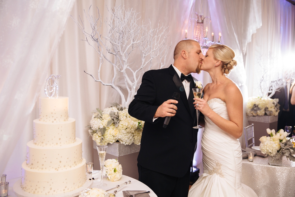 Bride and groom kissing in behind cake