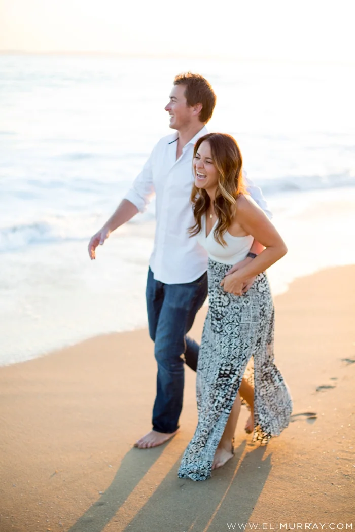 Engaged couple laughing on the beach