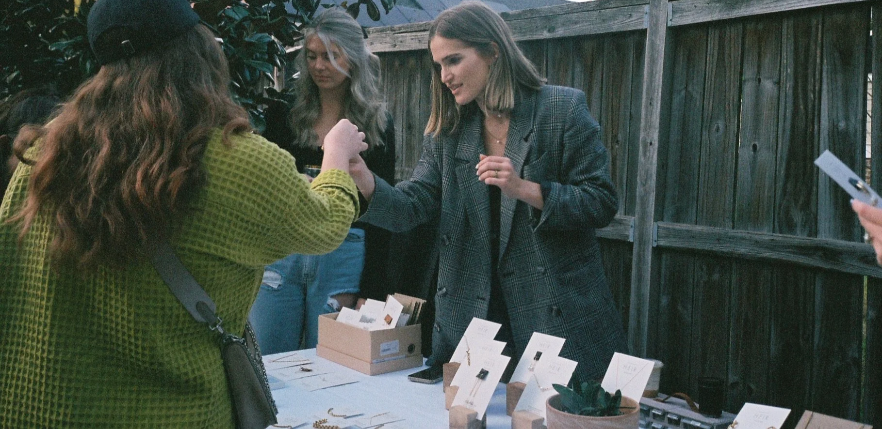 Sophie Wiseman-Floyd of HEIR Raleigh assisting a customer with jewelry at an outdoor pop-up event market.
