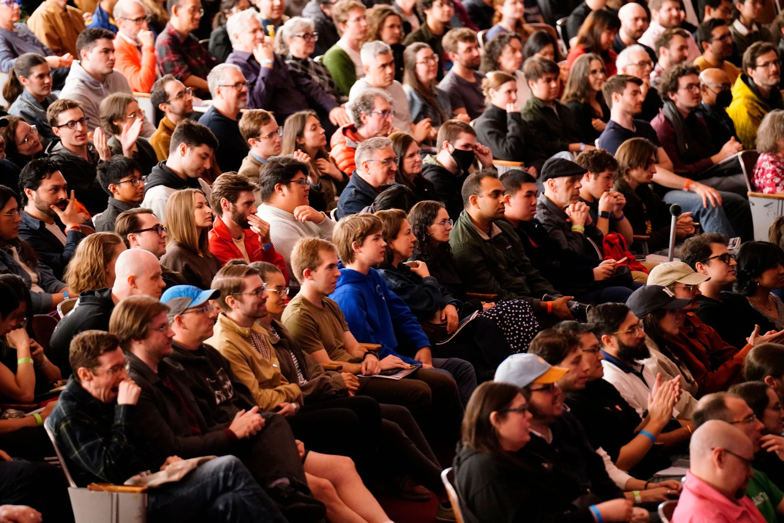 Audience attending a conference in an auditorium, sitting and listening to a speaker.