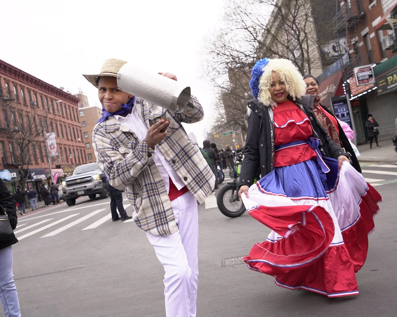 People dressed in colorful costumes walking on a city street during a parade or celebration.