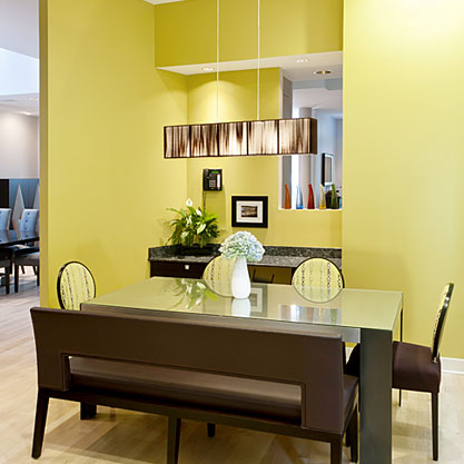 A kitchen nook that previously housed a banquette was redesigned and enlarged to incorporate a work space and new eating area. Existing windows were removed and larger ones installed to add more light. A large pendant light hangs over a custom made metal table creating an intimate, fun and functional area for the family to enjoy. A bright citron color present on the walls and accented in the upholstery adds energy to the space.