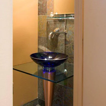 An existing powder room was gutted and updated using a gold and green slate tile and custom made vanity.