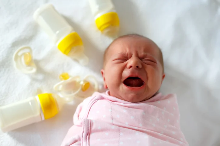 Baby Crying Surrounded By Bottles And Pacifiers.jpg