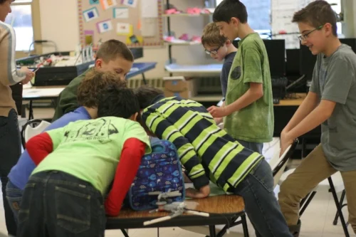  STEM Explorers crowding in to look at a two gear spinner  