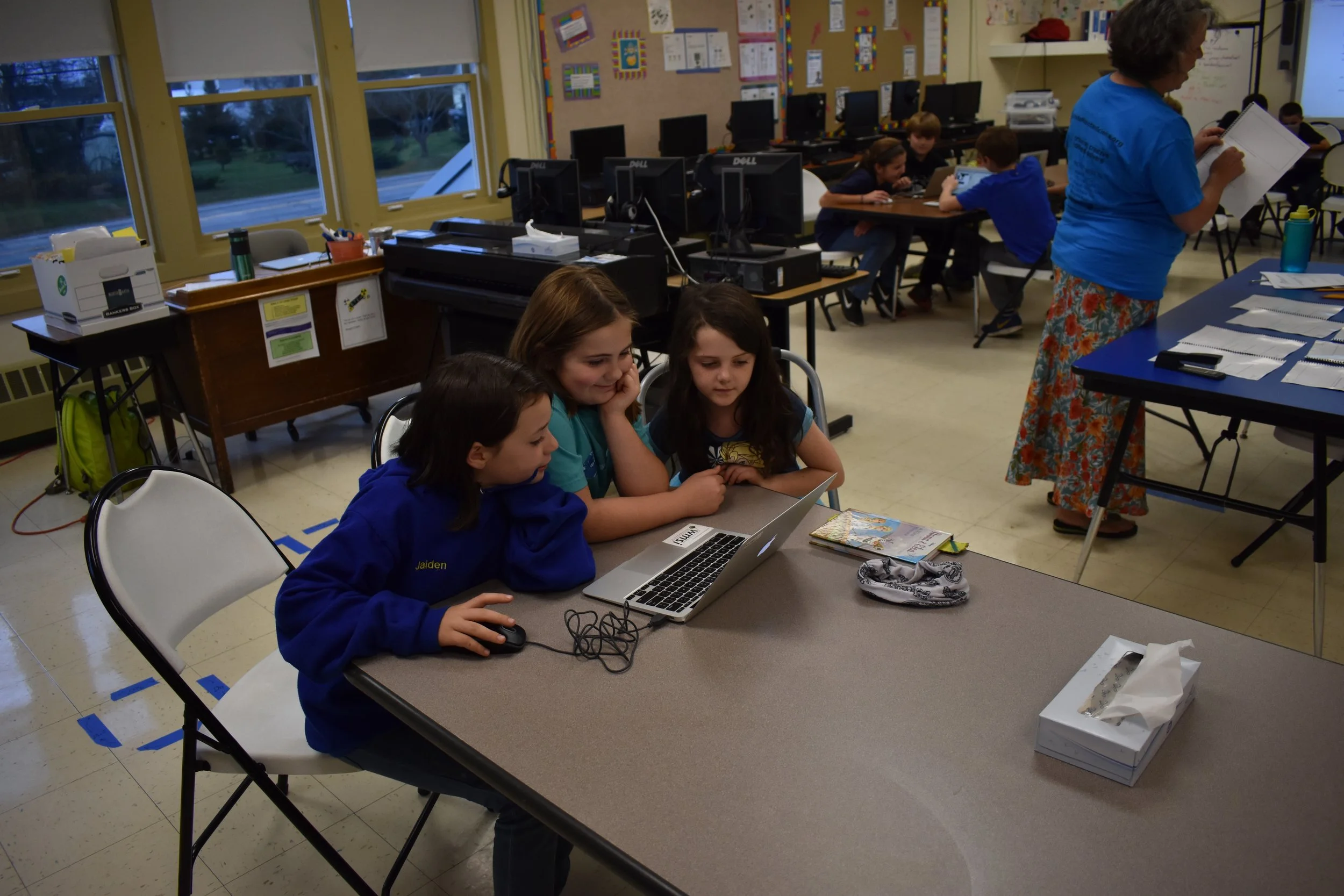 Three friends hard at work coding a story about a brave monkey explorer!