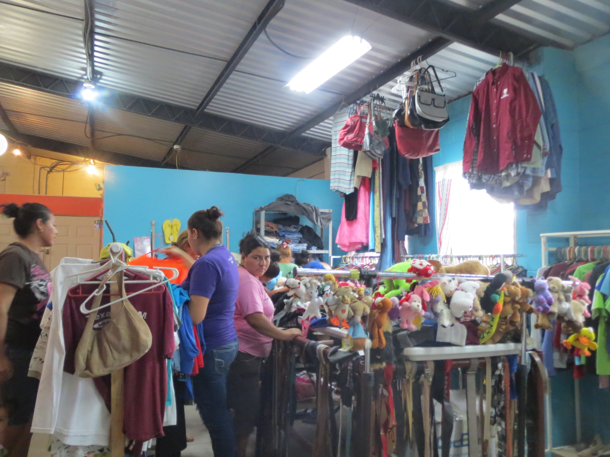 Salvadoran women selecting gently used clothes they will sell as part of the SonRia entrepreneurship program. 