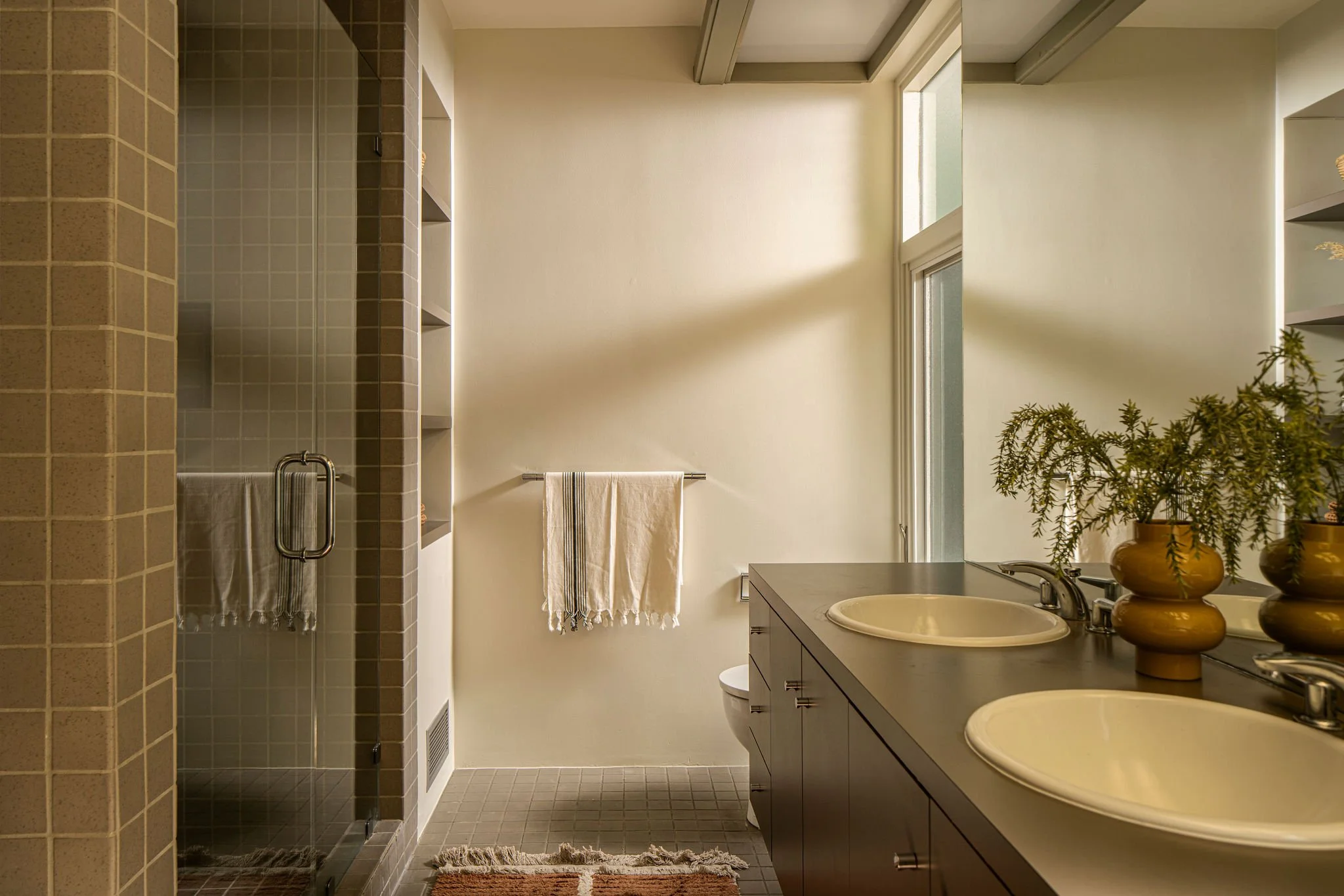 Updated mid-century modern bathroom with double vanity and tiled shower in Hollywood Hills home