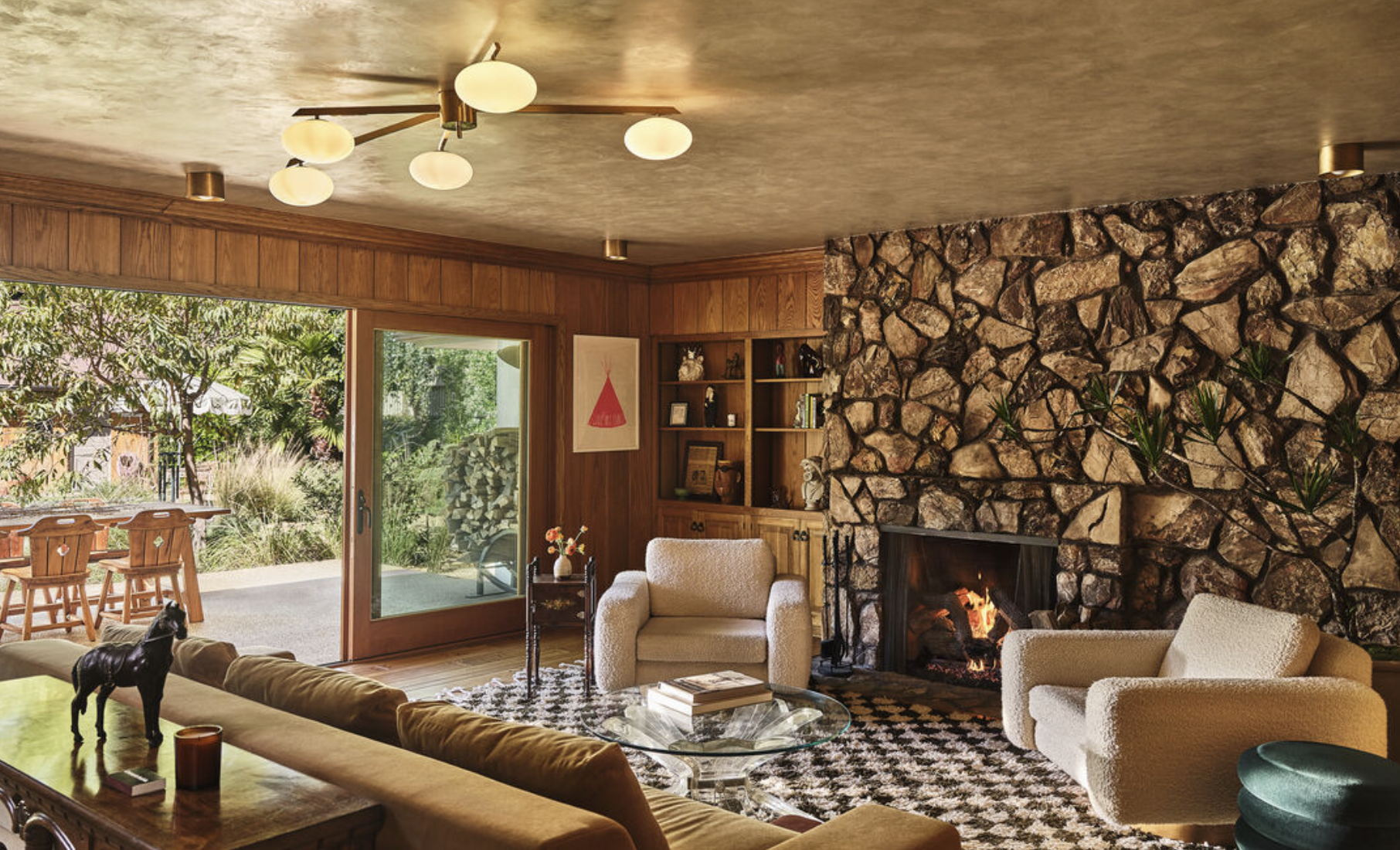 Grandmacore living room in Los Angeles featuring original stone fireplace, wood paneling, and vintage mid-century furnishings