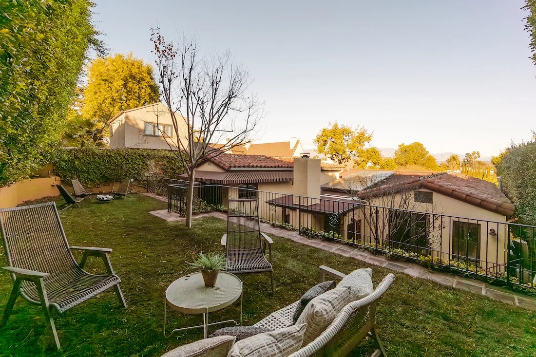 Terraced backyard with grassy lawn, tiled patios, mature landscaping, and a private setting ideal for outdoor dining, relaxation, and entertaining in Silver Lake.