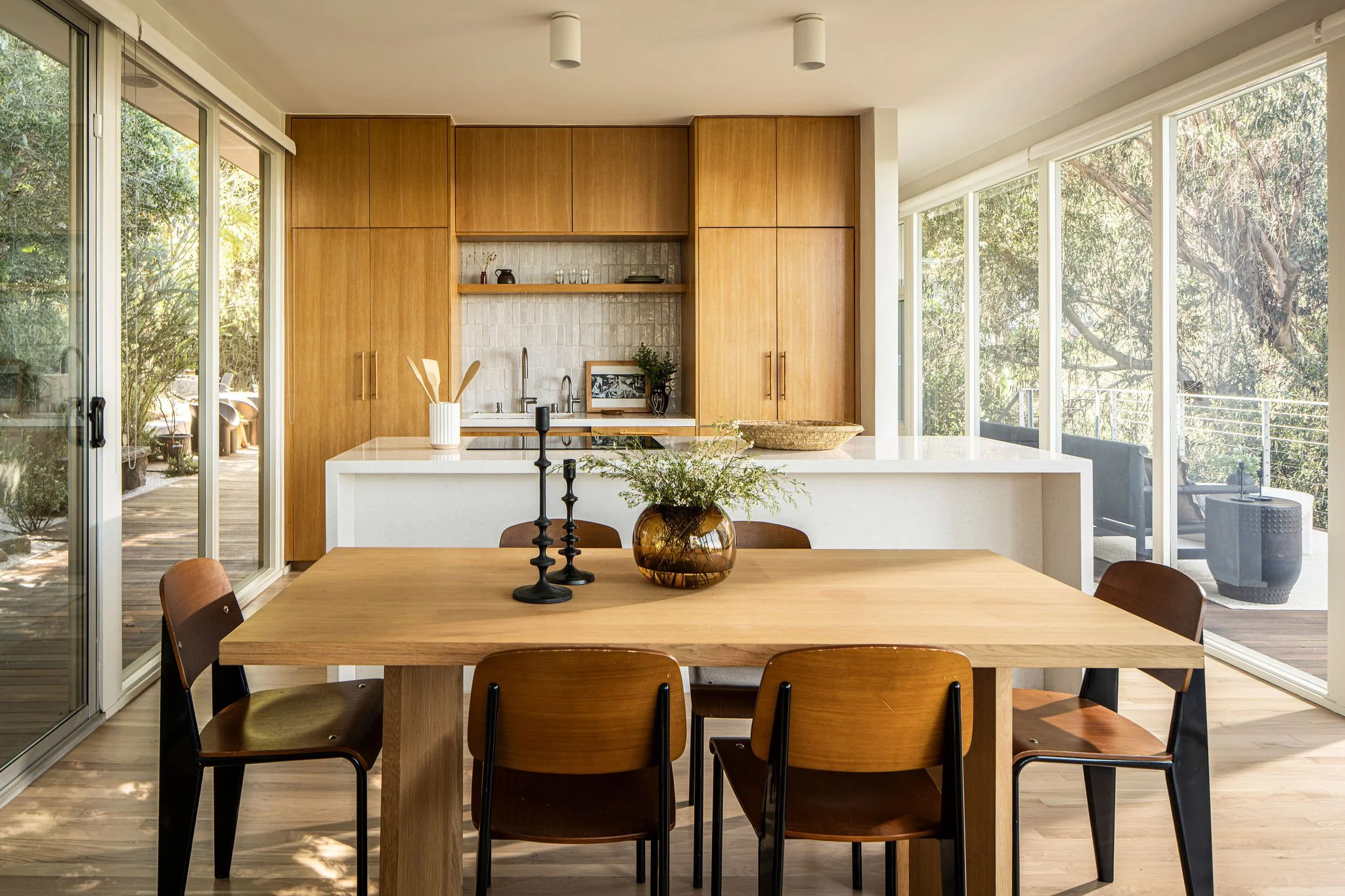 Mid-century modern kitchen with wood cabinetry and open-plan dining area in Los Angeles Caption: Warm wood cabinetry and clean lines keep the kitchen aligned with the home’s original architectural intent.