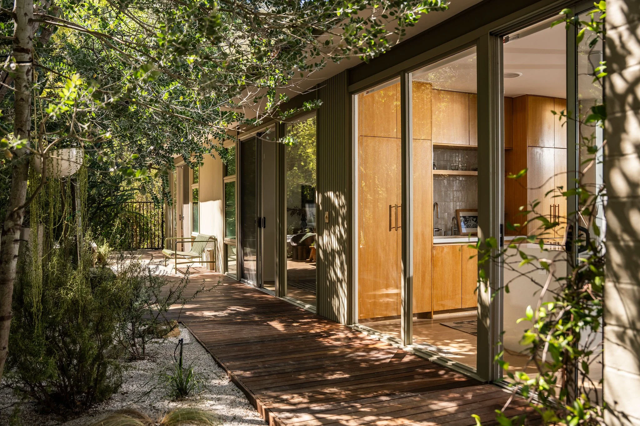 Mid-century modern home with sliding glass walls opening to outdoor walkway and garden in Hollywood Hills