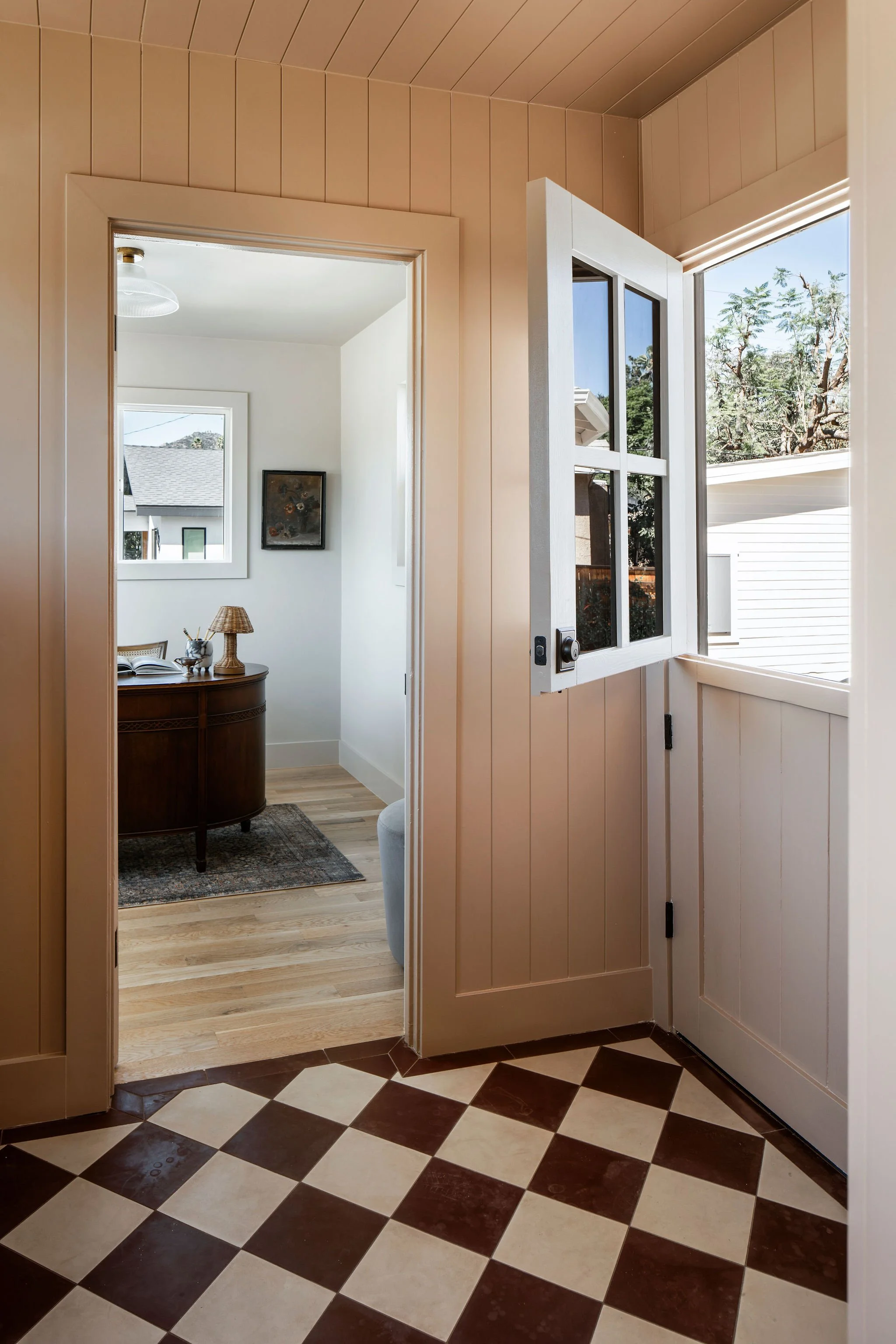 Interior laundry room in a 1924 Eagle Rock Craftsman with side-by-side washer and dryer, checkerboard floor tile, and wood-paneled walls.