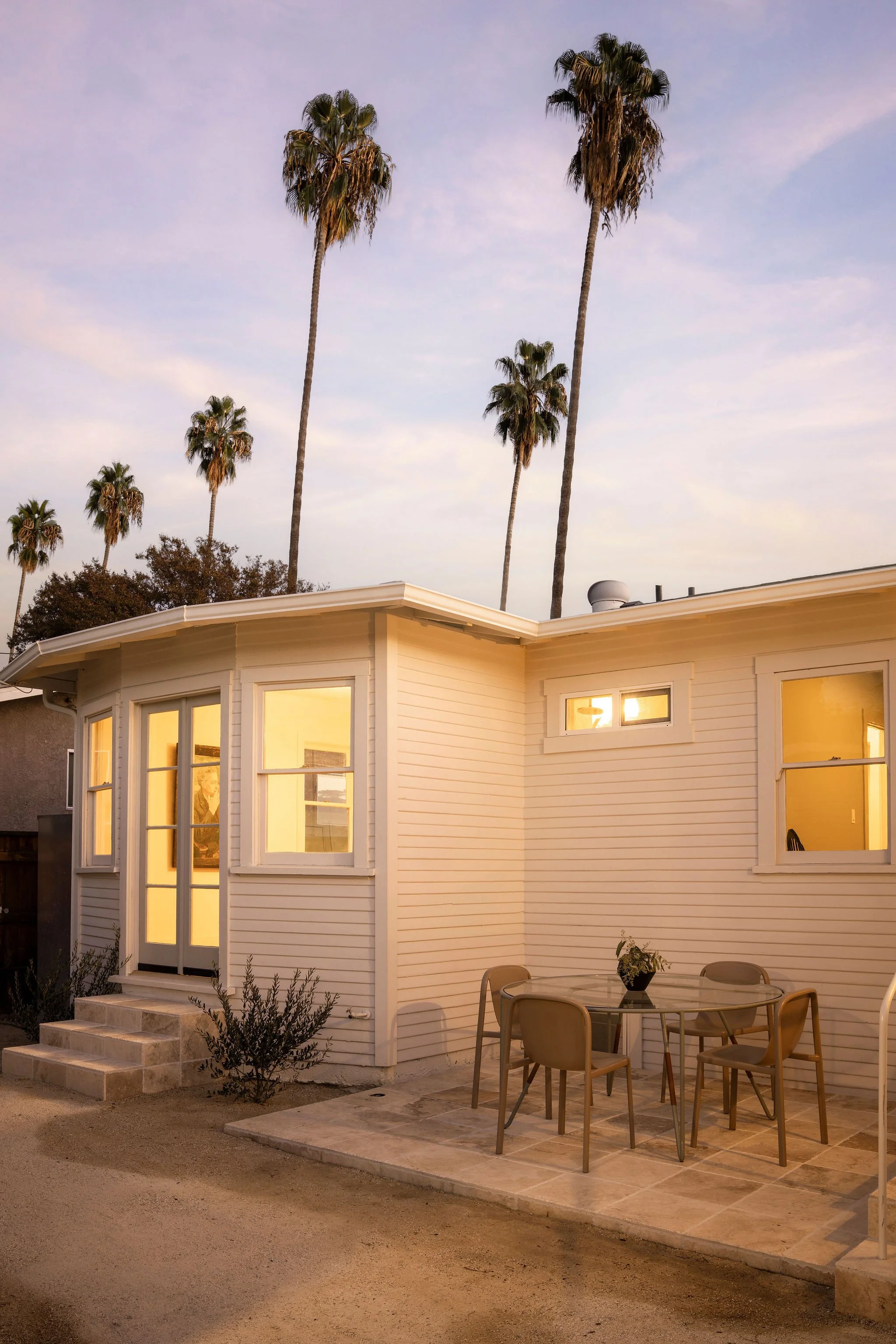 Outdoor dining patio at 1597 Fair Park Avenue in Eagle Rock with a dining table, French doors, garden landscaping, and palm trees at dusk.