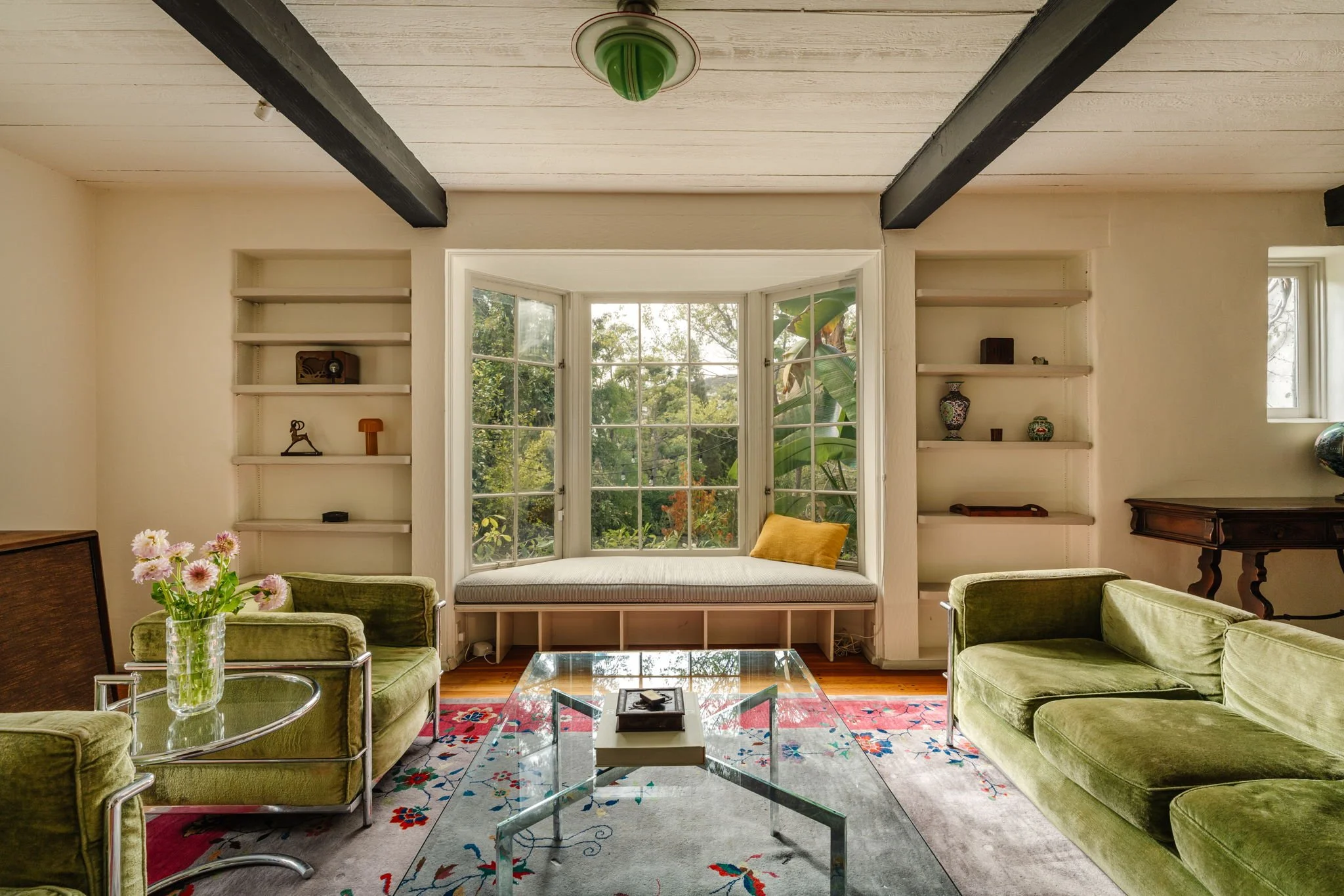 Living room with bay window seat, built-in shelves, and hillside greenery views in Whitley Heights Spanish home