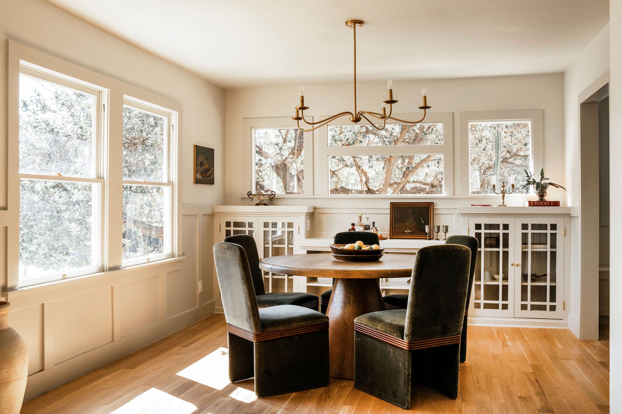 Formal dining room with original glass-front Craftsman built-in cabinets, wood paneling, oak floors, and large windows at 1597 Fair Park Avenue.