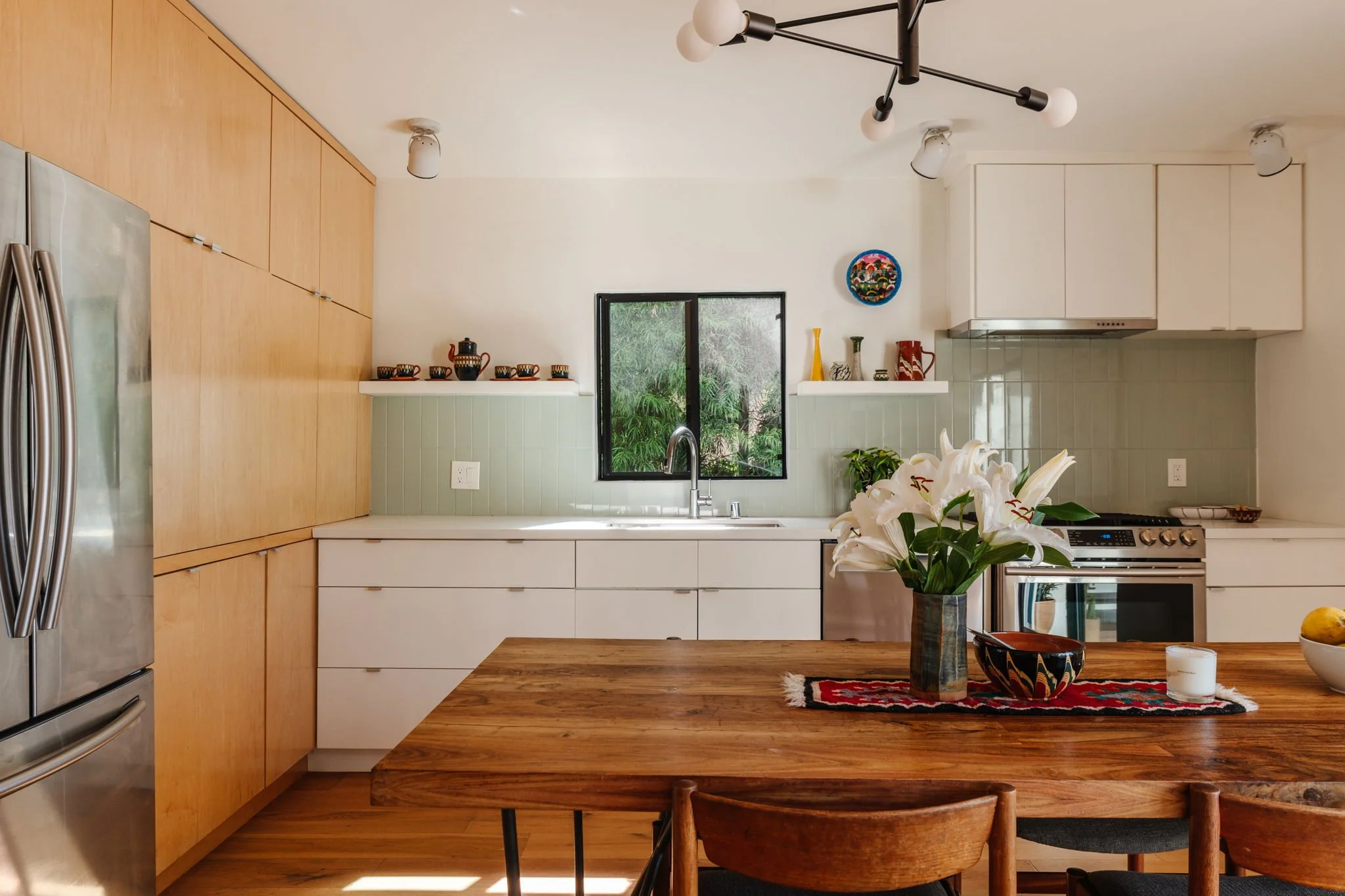 Modern kitchen in Highland Park home for sale with green tile backsplash, flat panel cabinetry, and wood accents