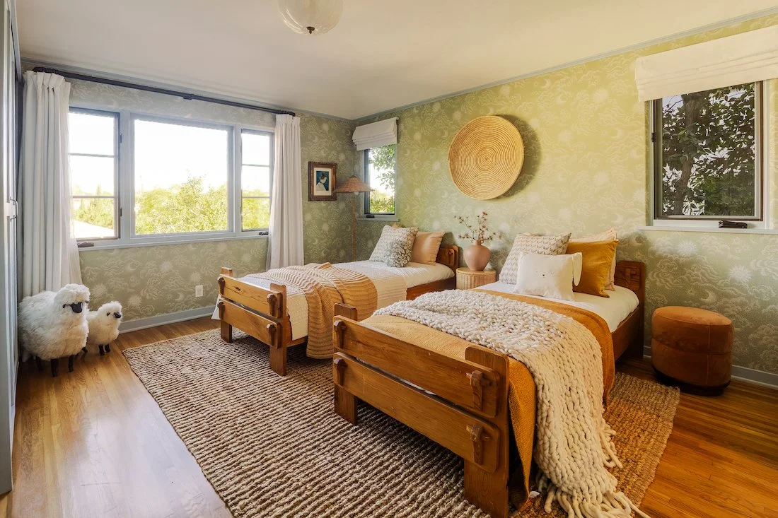 Bright bedroom featuring original wood floors, garden-facing windows, and vintage architectural details consistent with the home’s 1929 Spanish Revival design.