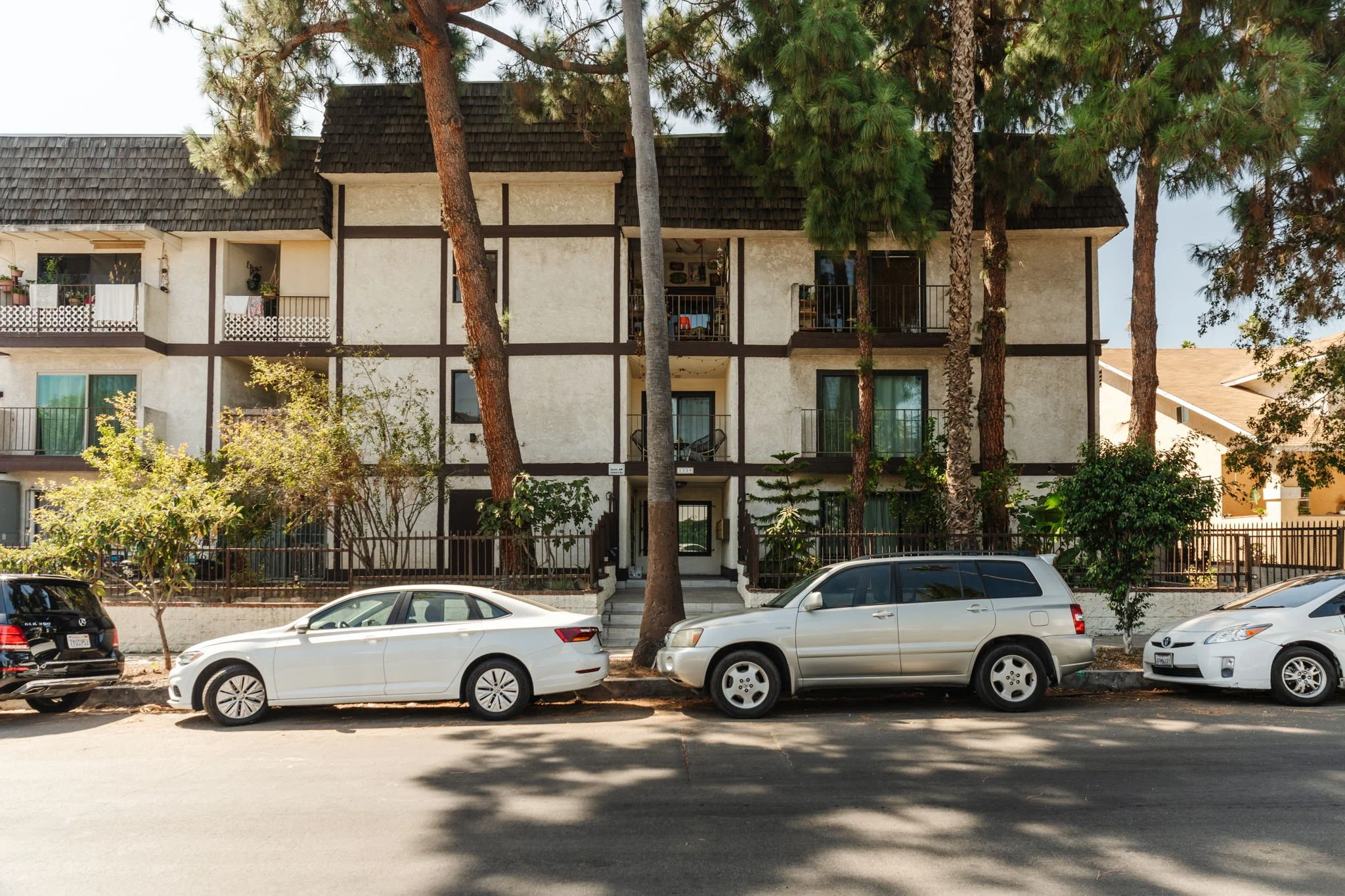 Condominium building at 1559 Winona Blvd with dark exterior trim, balconies, and mature trees along the street.