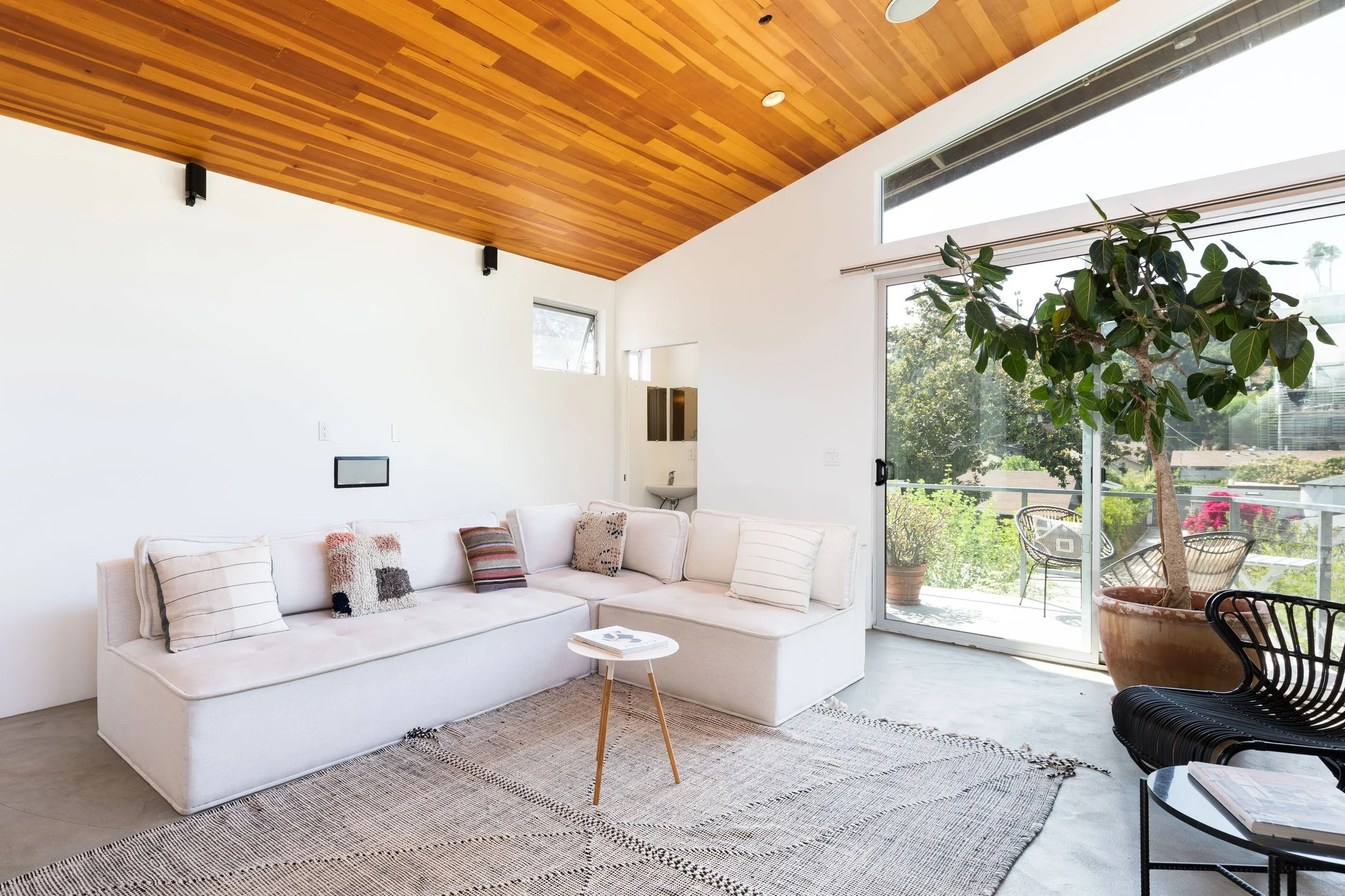 Modern living room with a soaring wood ceiling and sliding glass doors opening to an outdoor sitting area.