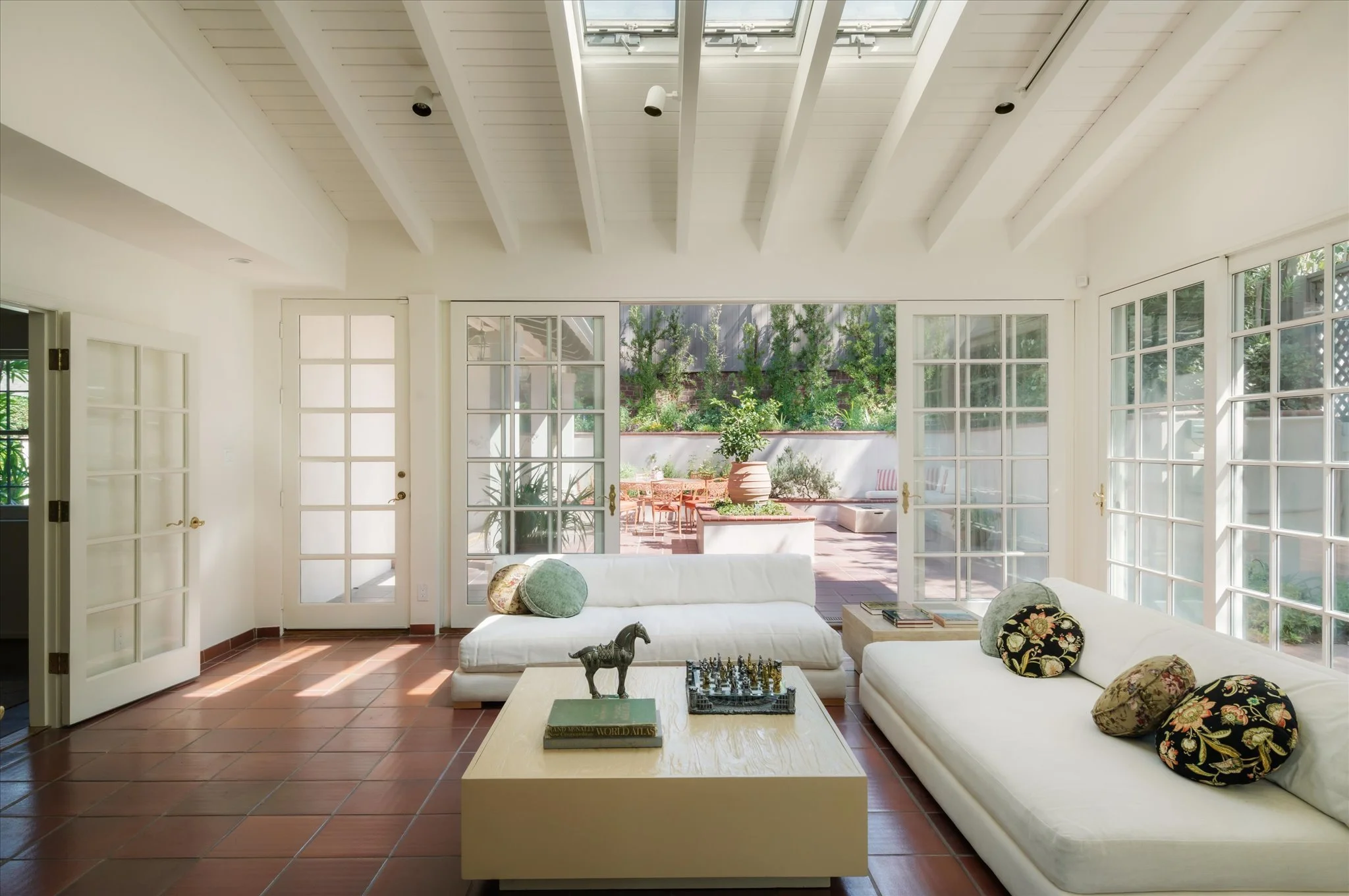 Vaulted sunroom with beamed skylight ceilings and French doors opening to the private patio.