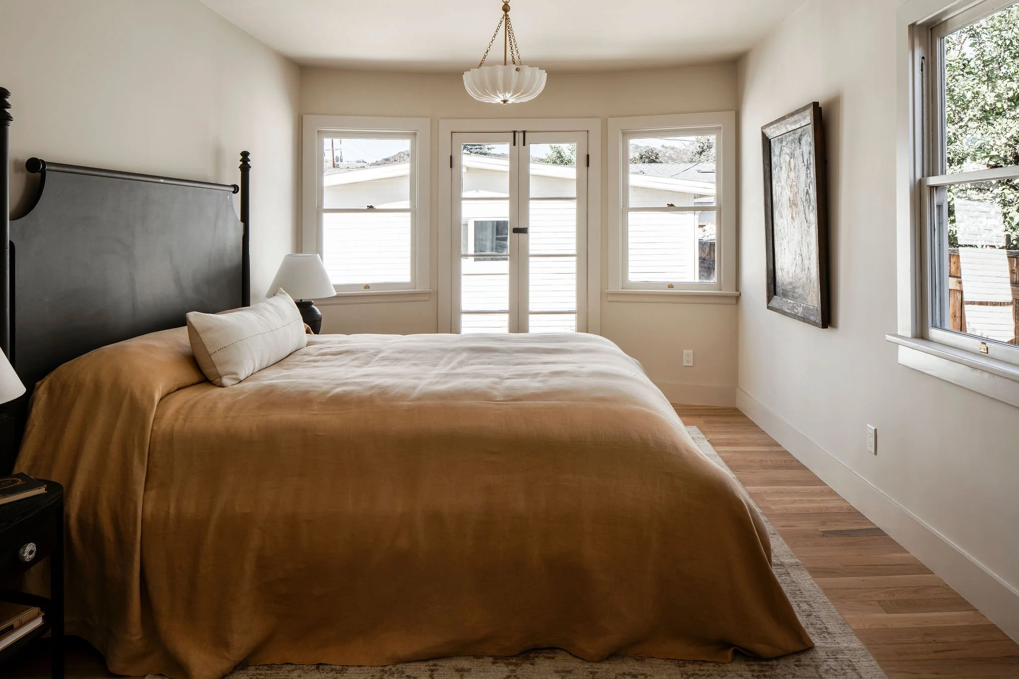 Bright bedroom at 1597 Fair Park Avenue with solid oak flooring, restored wood windows, and French doors opening toward the backyard garden.