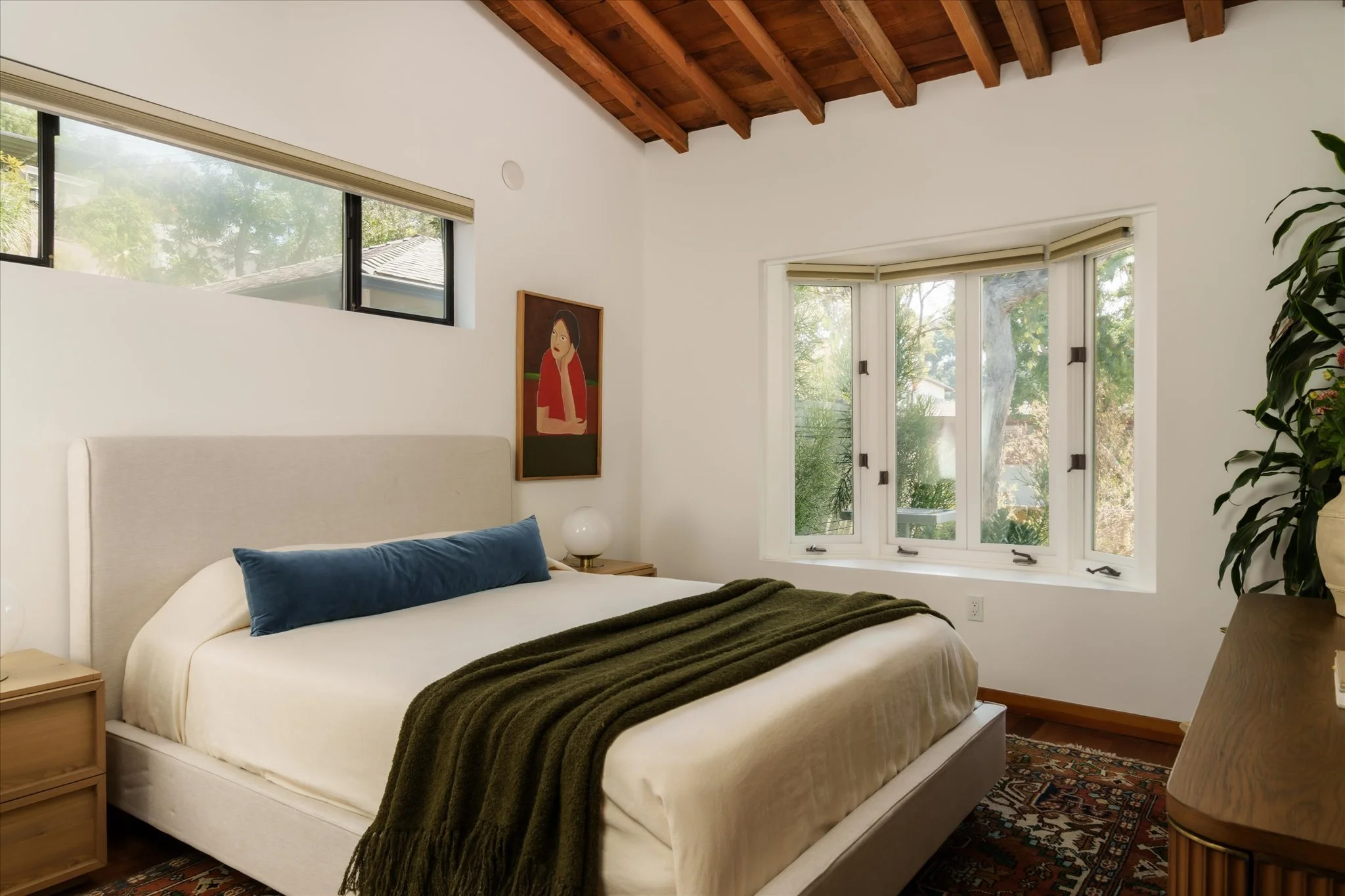 Bedroom with vaulted wood ceilings, exposed beams, and a bay window overlooking greenery at 1811 Micheltorena St in Silver Lake.