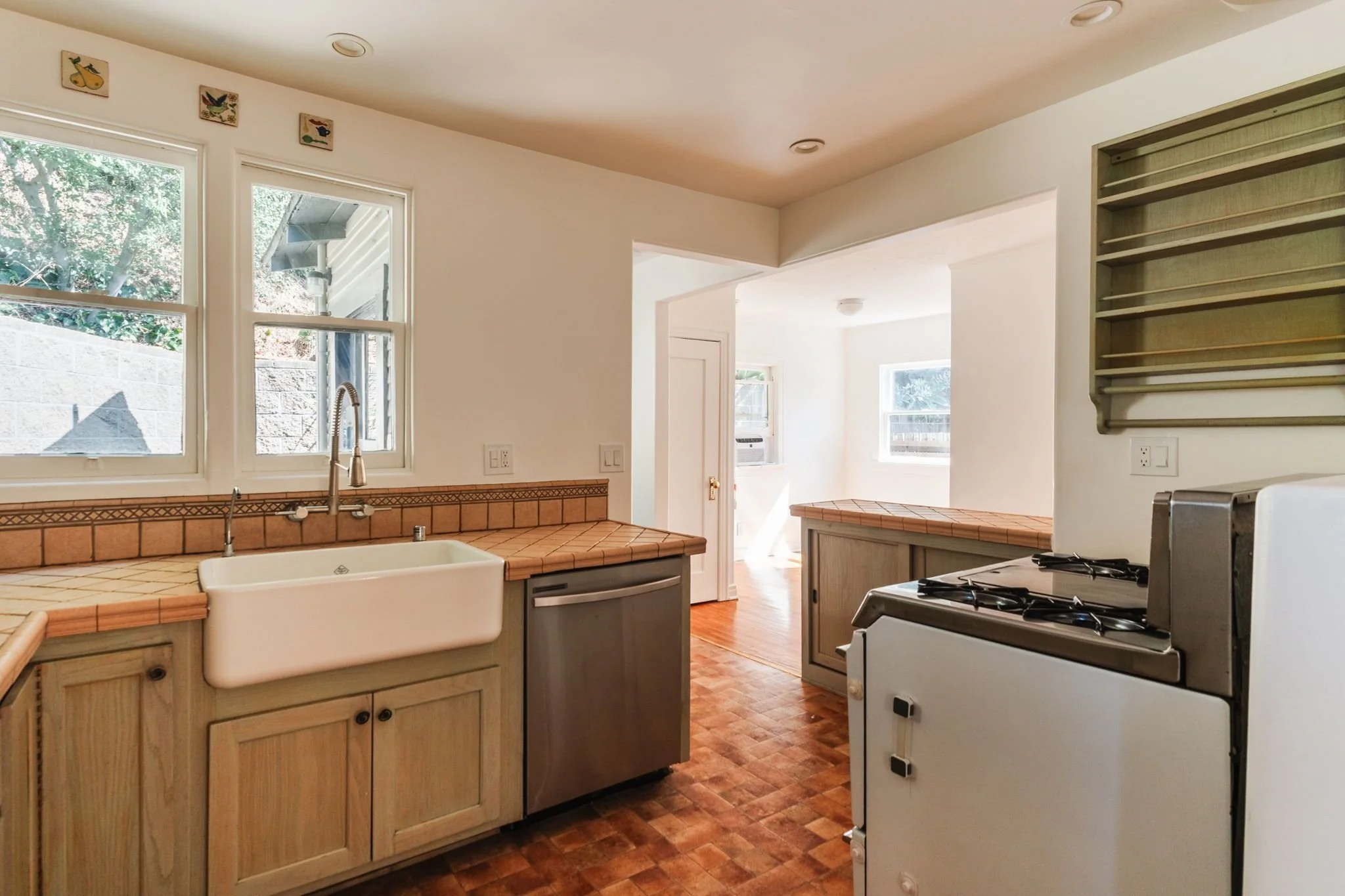 Bungalow kitchen with tile countertops, a farmhouse sink, wood cabinetry, and a vintage O’Keefe & Merritt stove.