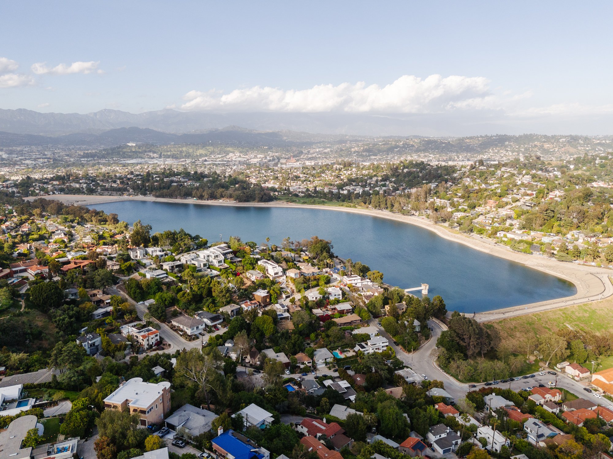 Aerial view of the Silver Lake Reservoir surrounded by hillside homes with the San Gabriel Mountains in the background