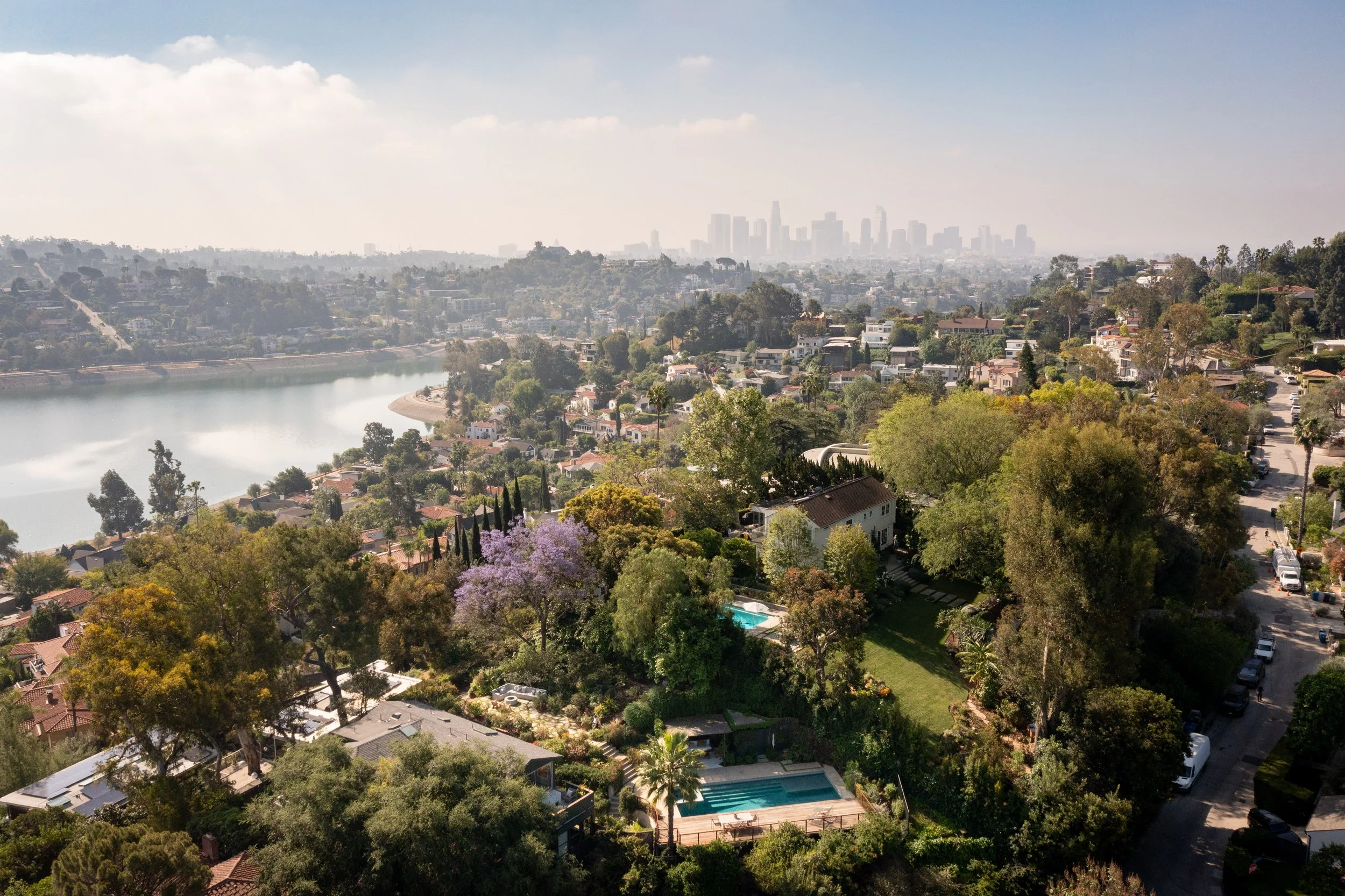 Aerial view of Silver Lake Los Angeles hillside homes overlooking the reservoir and downtown skyline, showcasing a competitive real estate market with multiple offers