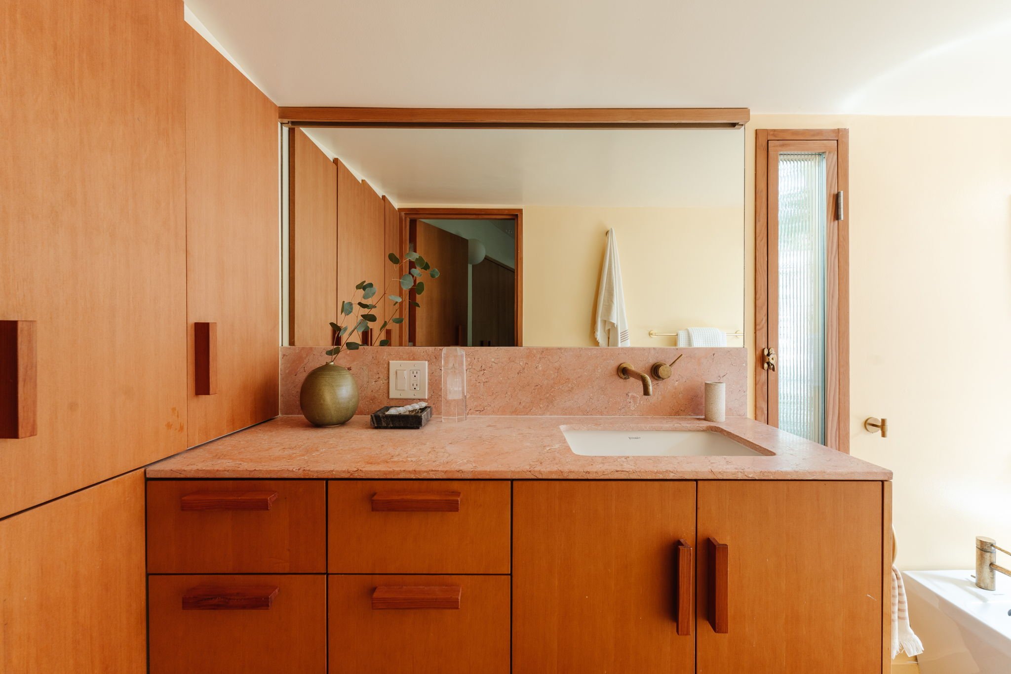 Modern bathroom with stone countertops, wood cabinetry, and warm finishes in Silver Lake home