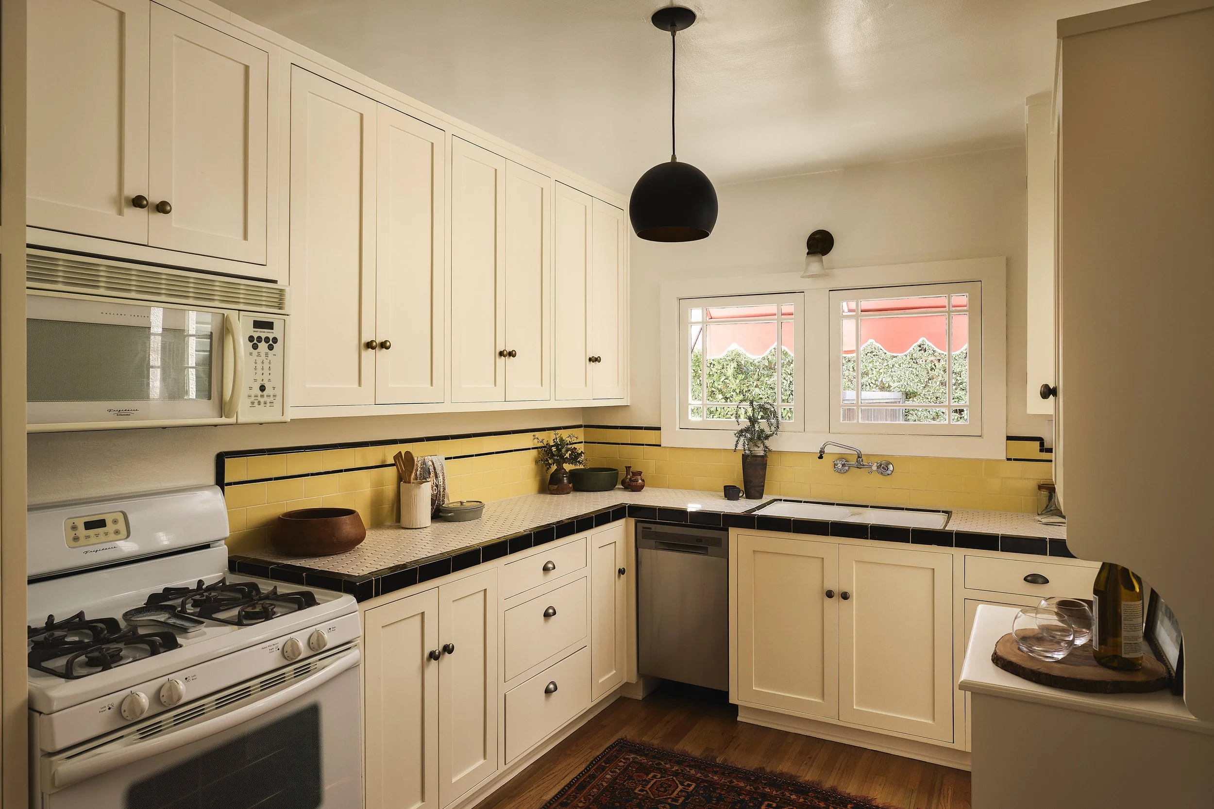 Vintage kitchen with yellow tile countertops, white cabinetry, and updated appliances in a Spanish-style home in Adams Hill Glendale