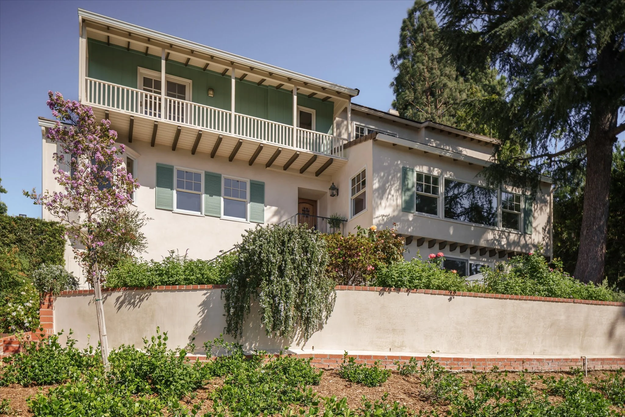 Front exterior of 2560 Micheltorena St, a 1936 Monterey Colonial in Silver Lake's Moreno Highlands, with an upper balcony and landscaped front garden.