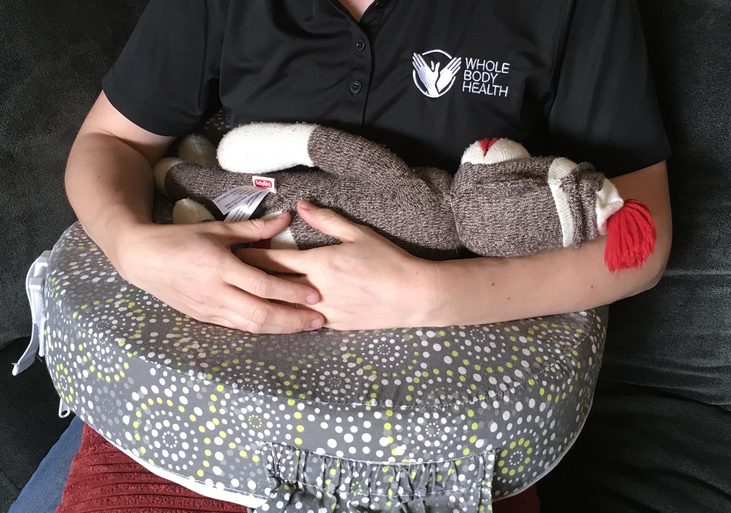 A nursing pillow with a red couch cushion to bring it up even higher