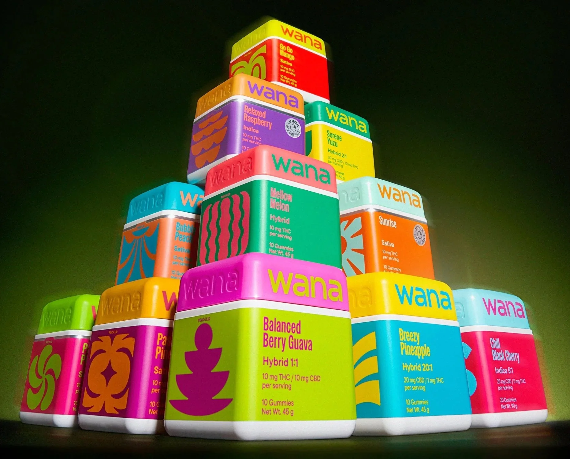 Colorful stacks of cannabis edible containers with different flavors such as Serene Yuzu, Melon Melon, Breezy Pineapple, and Chill Black Cherry, arranged in a pyramid shape against a dark background.