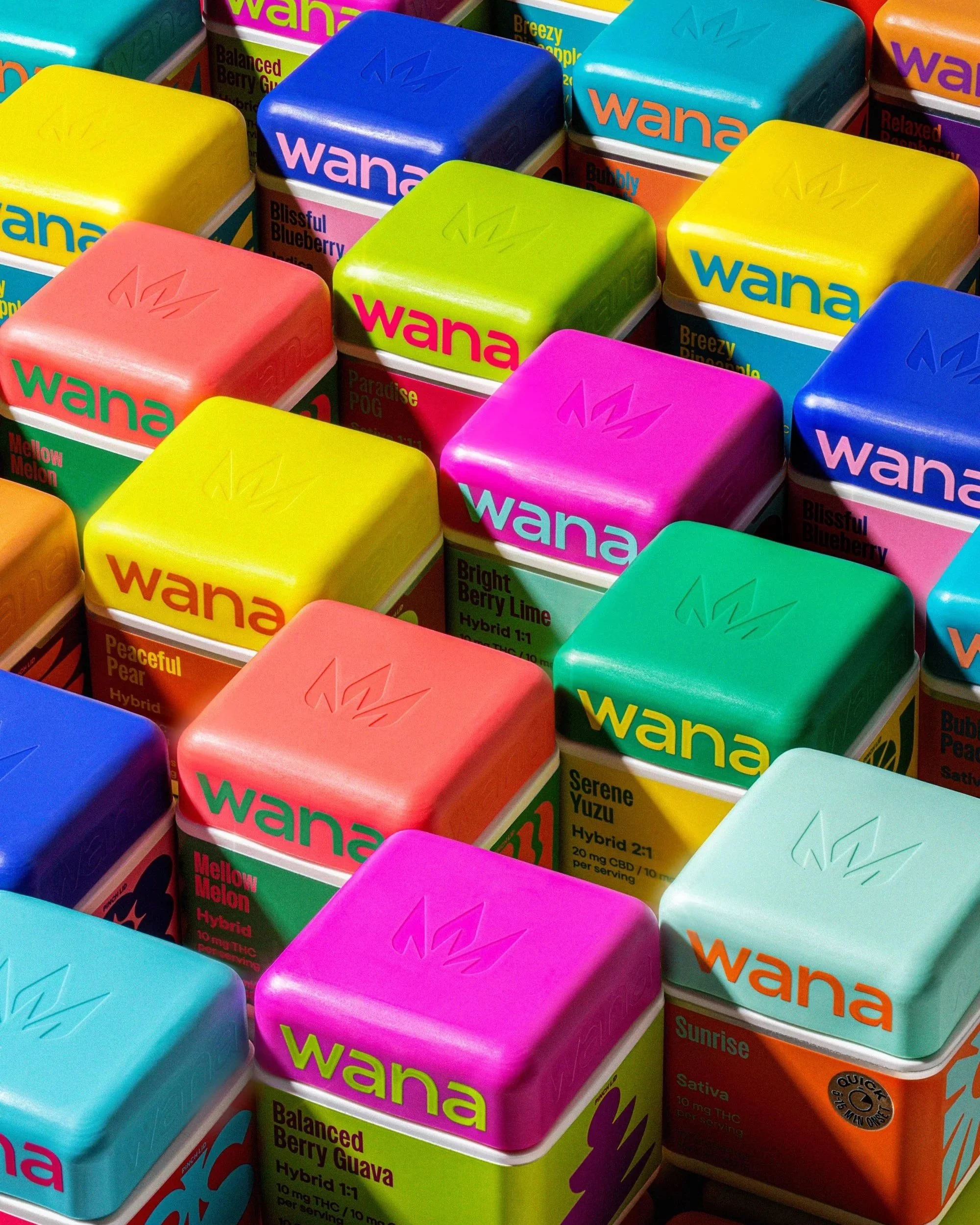 Colorful boxes of Wana CBD products with fruit flavors, such as Blueberry and Pear, arranged in a display.