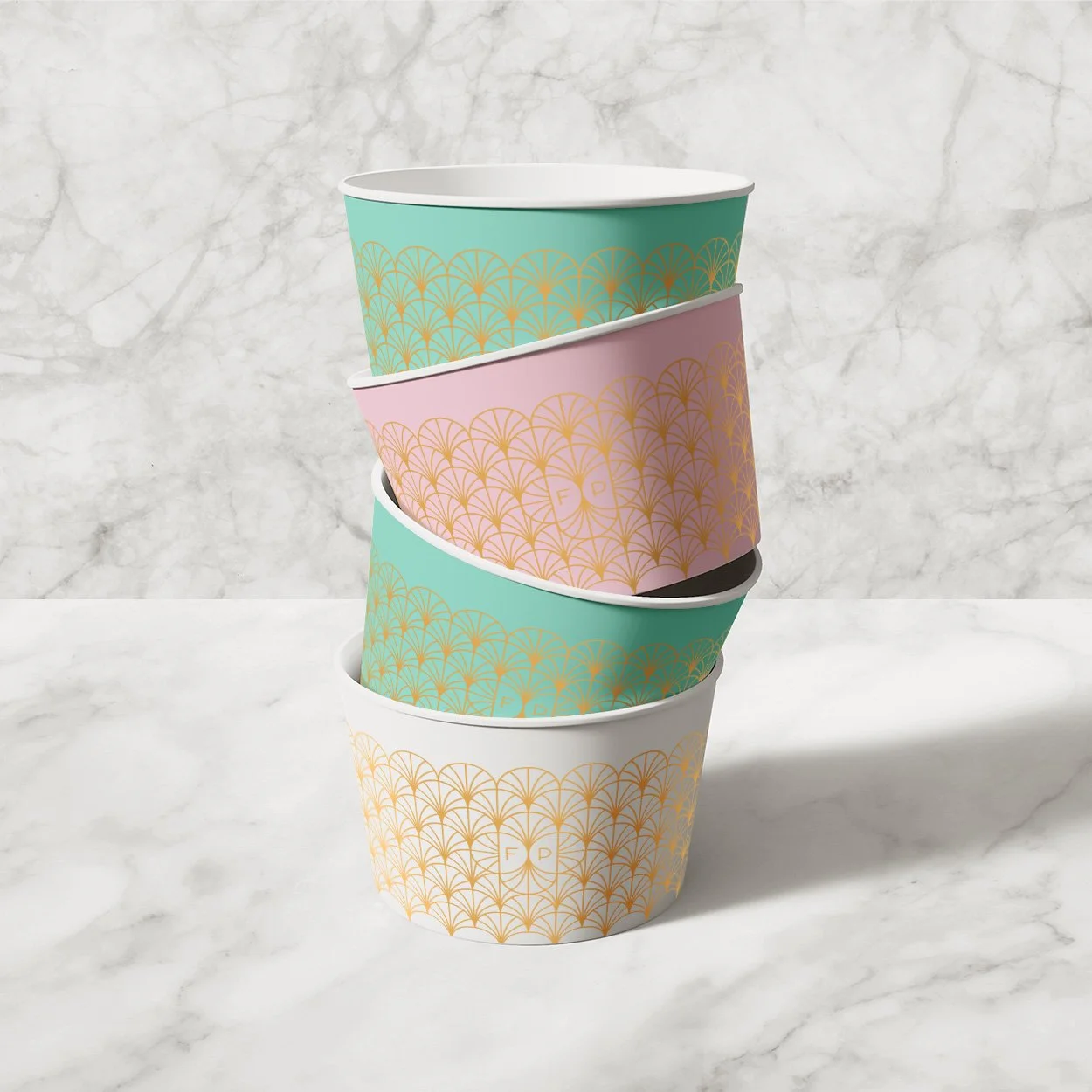 Four stacked paper cups with a decorative gold pattern on a marble background.