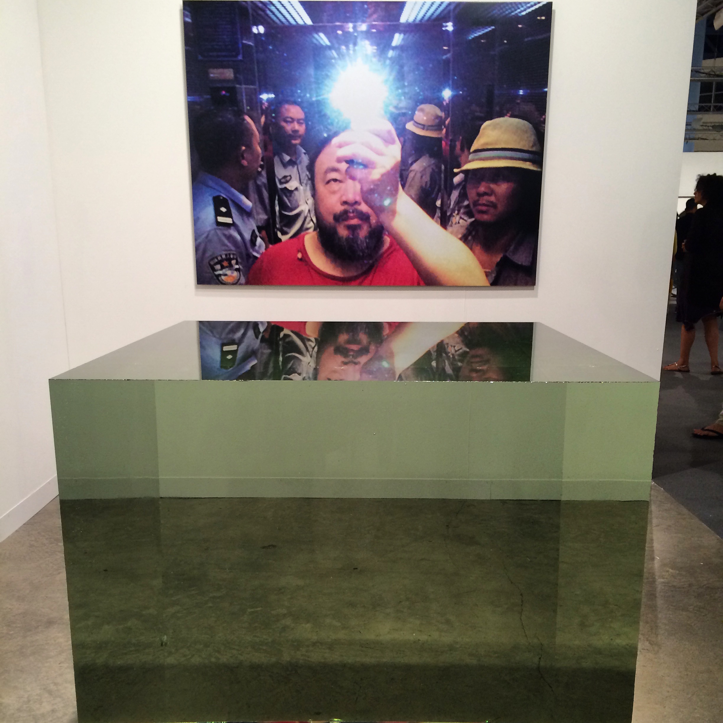 Ai Weiwei. Photograph and Crystal Cube, 2014. Crystal (leaded glass) cube 100 x 100 x 100 cm (1 cubic meter). Singular. Neugerriemschneider, Berlin.Ai WeiWei's singular photo shows his arrest, taken in elevator with arresting policemen. His hand and…