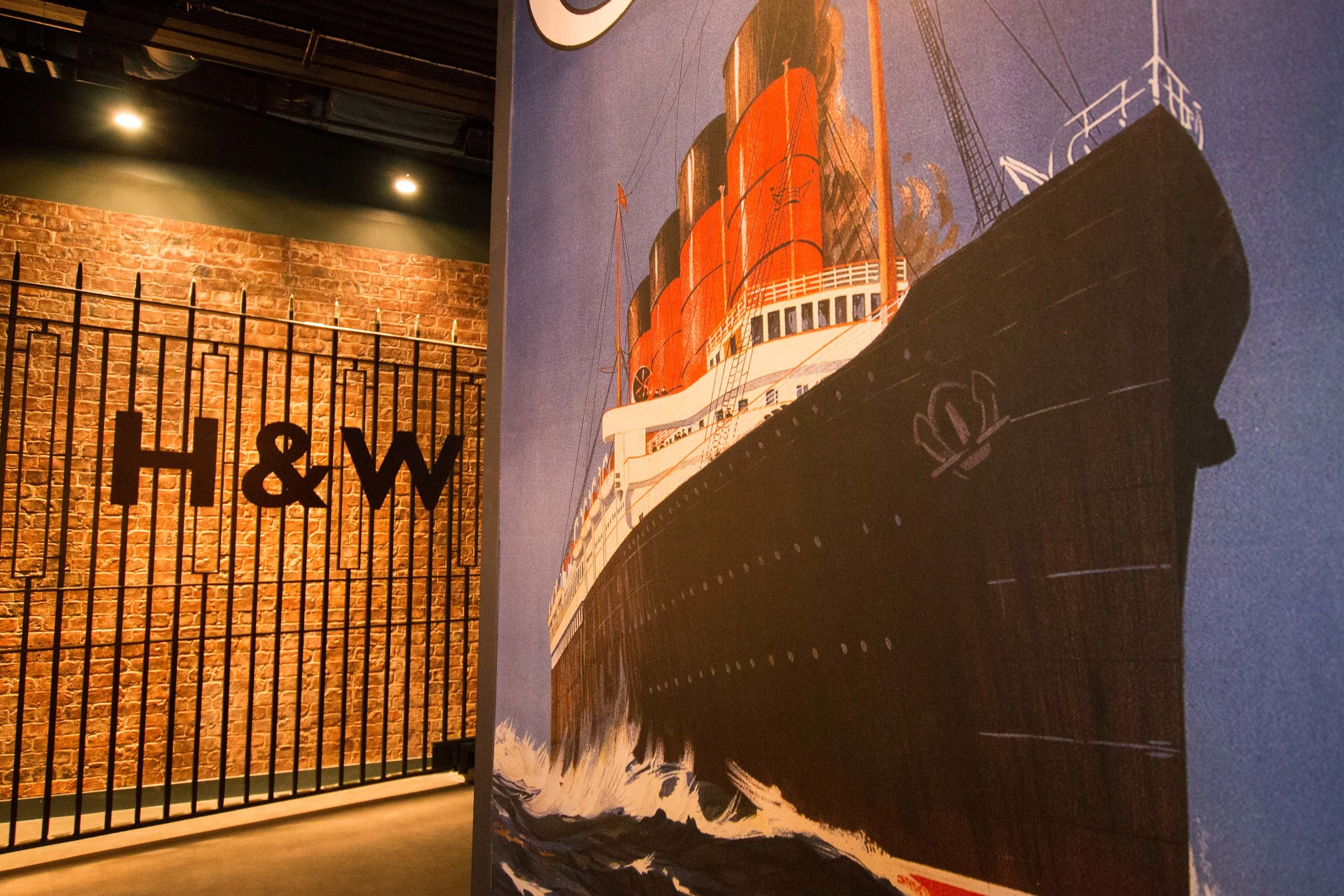 A mural of the Titanic with the actual gates from the Harland and Wolff shipyard from the Titanic era in the background.
