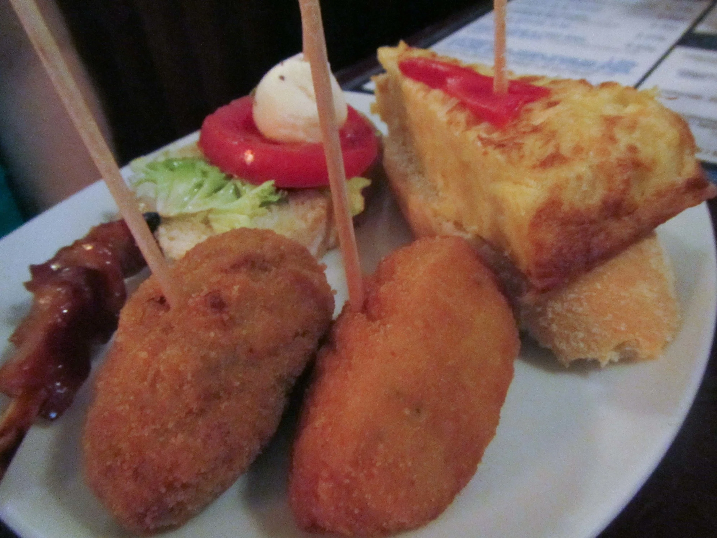 croquettes, capresse bread, potato quiche and some sort of meat on a stick