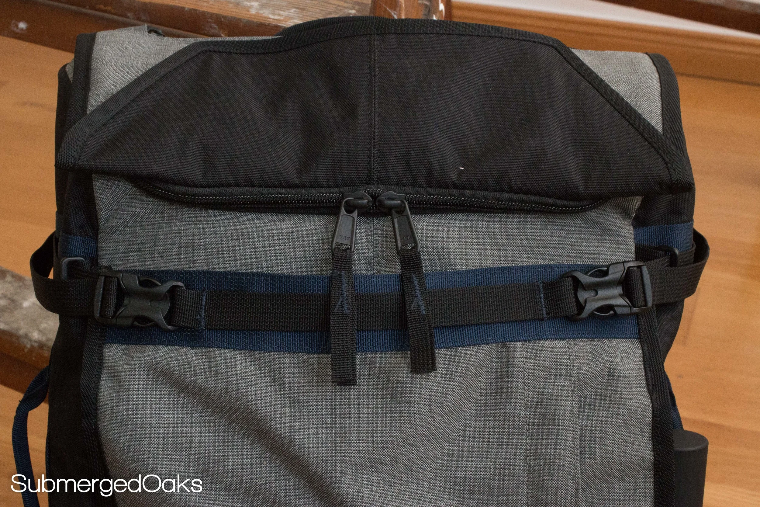 The top pocket has a double zipper and a buckle to close it