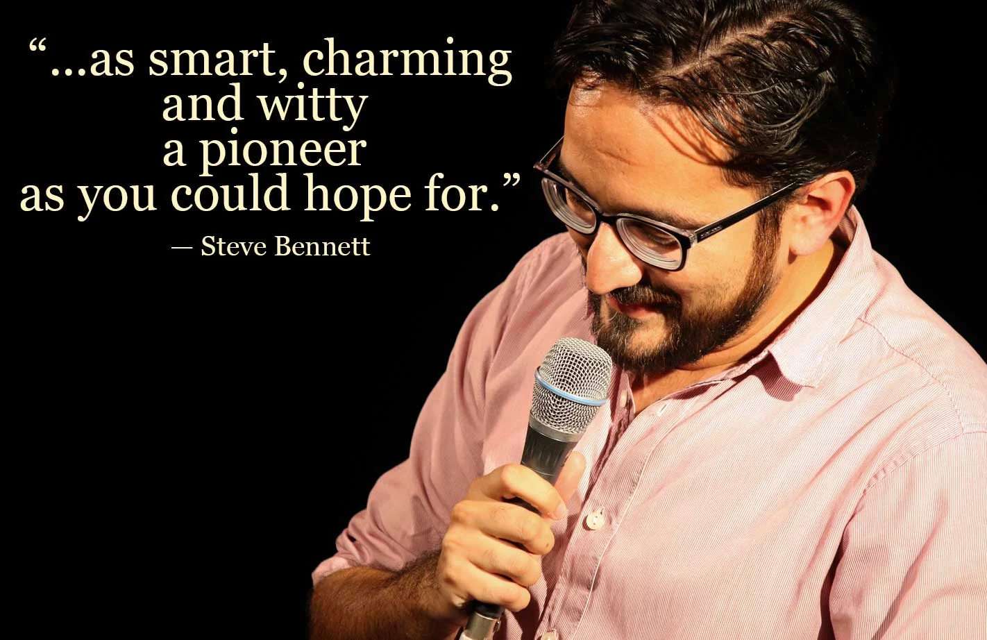 A man with glasses and a beard, wearing a pink shirt, stands against a black background, holding a microphone. A quote by Steve Bennett is displayed next to him, which says, '...as smart, charming and witty a pioneer as you could hope for.'