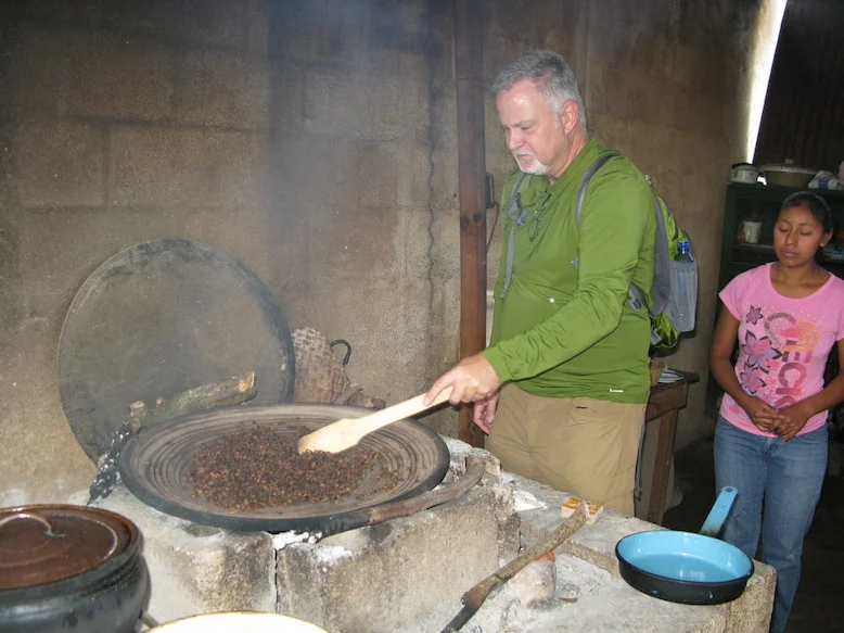 A tour participant roasts coffee beans, under the watchful eye of one of Filiberto's daughters.