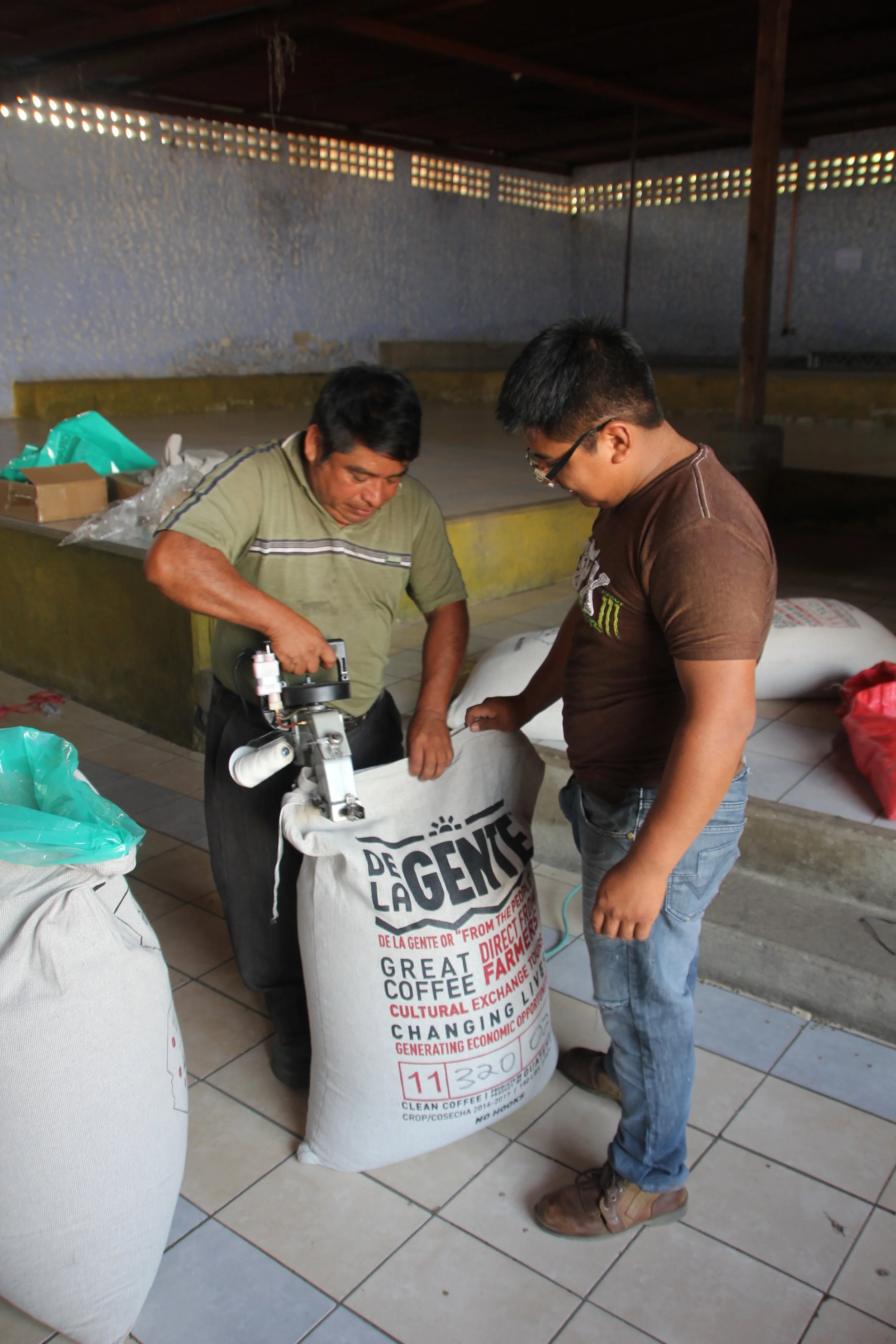 Fredy and his son sewing the bags shut, the final step in the bagging process