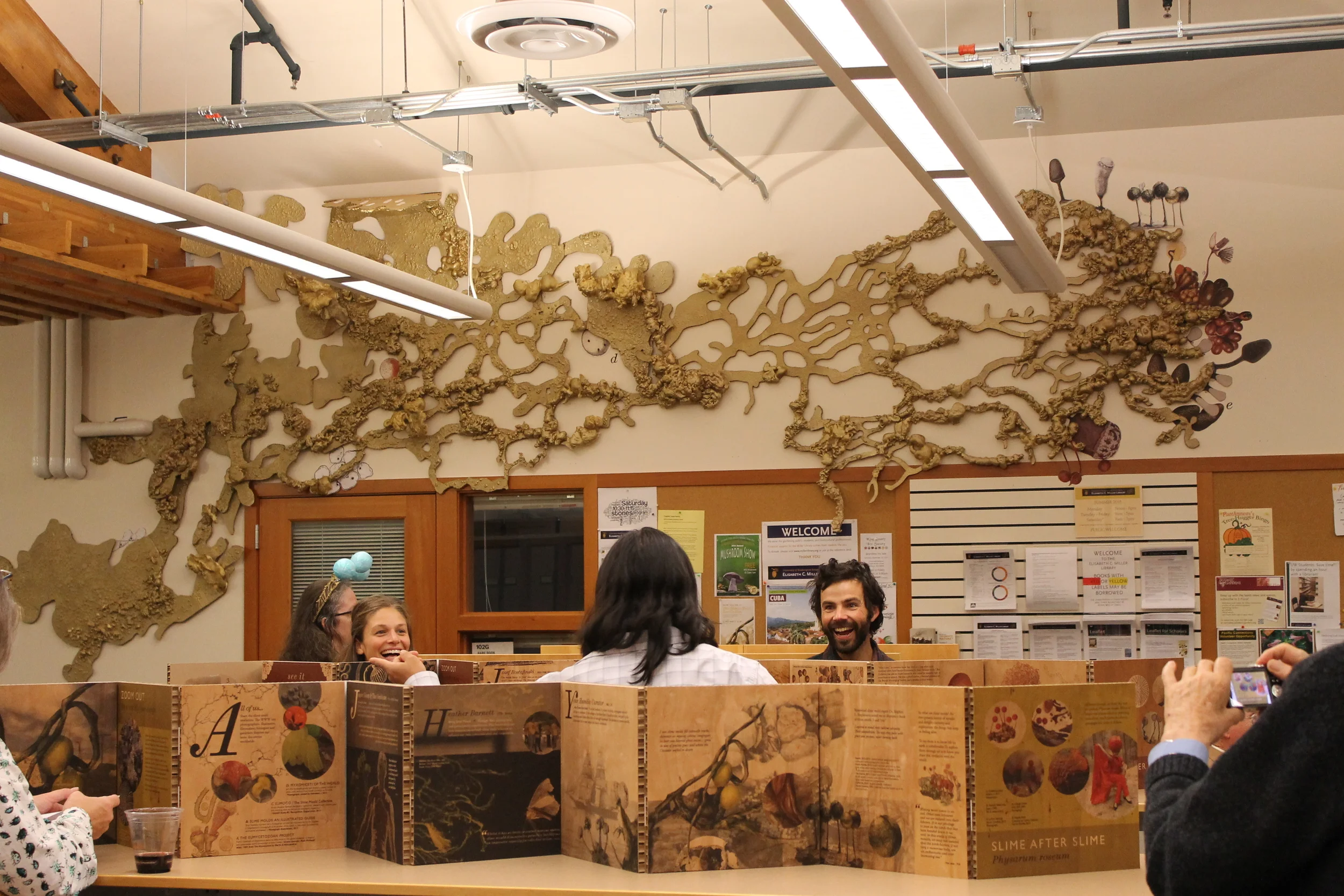 The plasmodium spreads above a graphic timeline about 400 years of artists devoted to slime molds. 