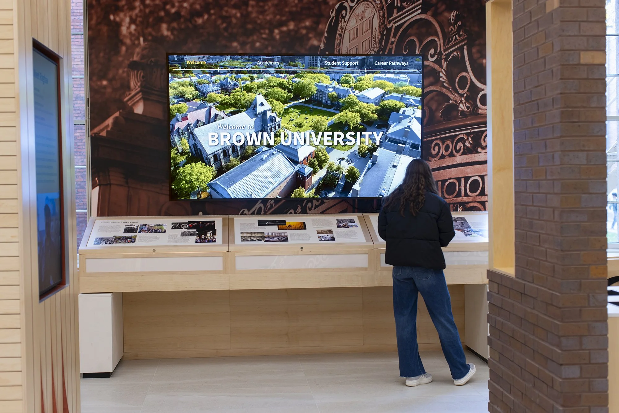 Student standing in front of a looped video on a large monitor