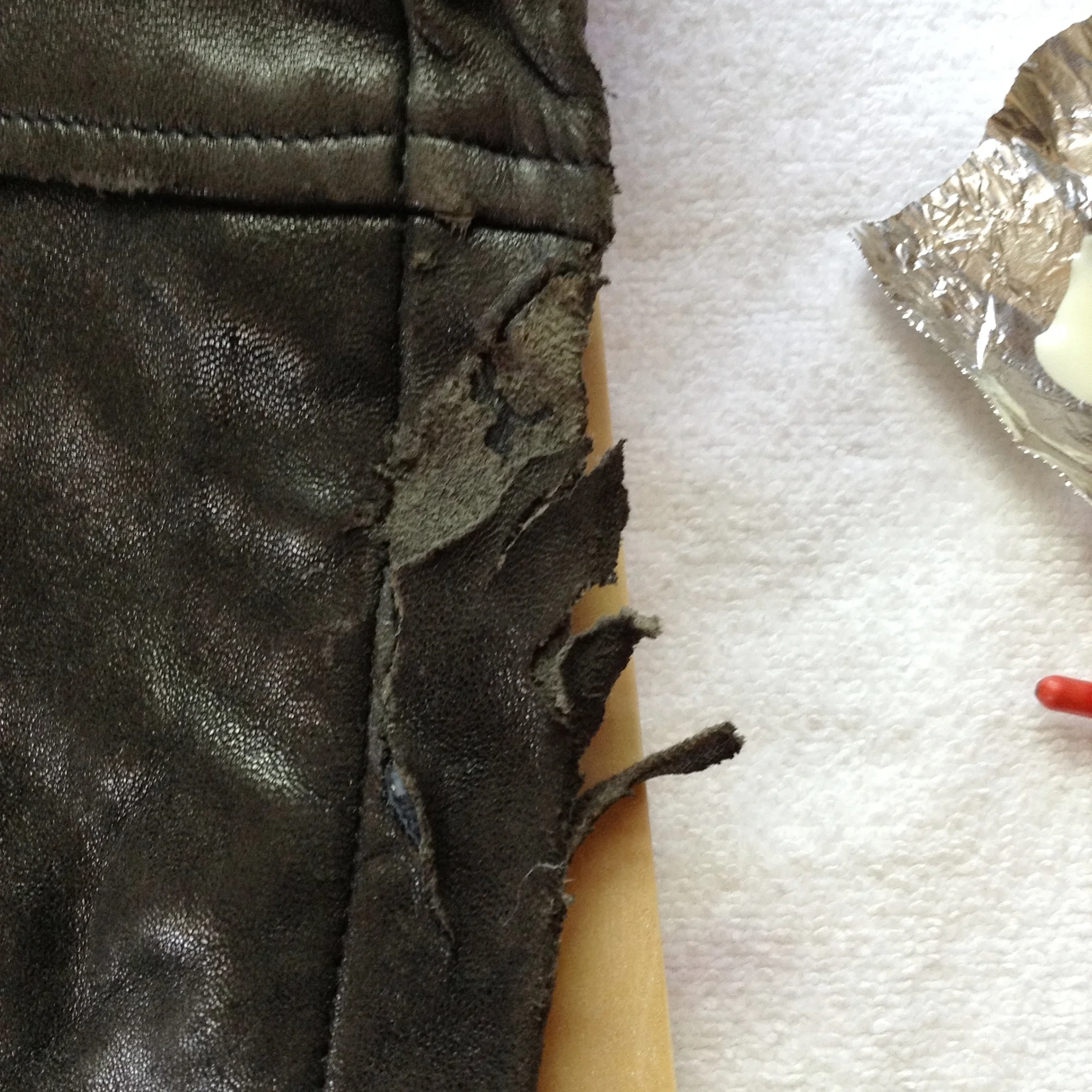 Torn leather jacket hem, "before".