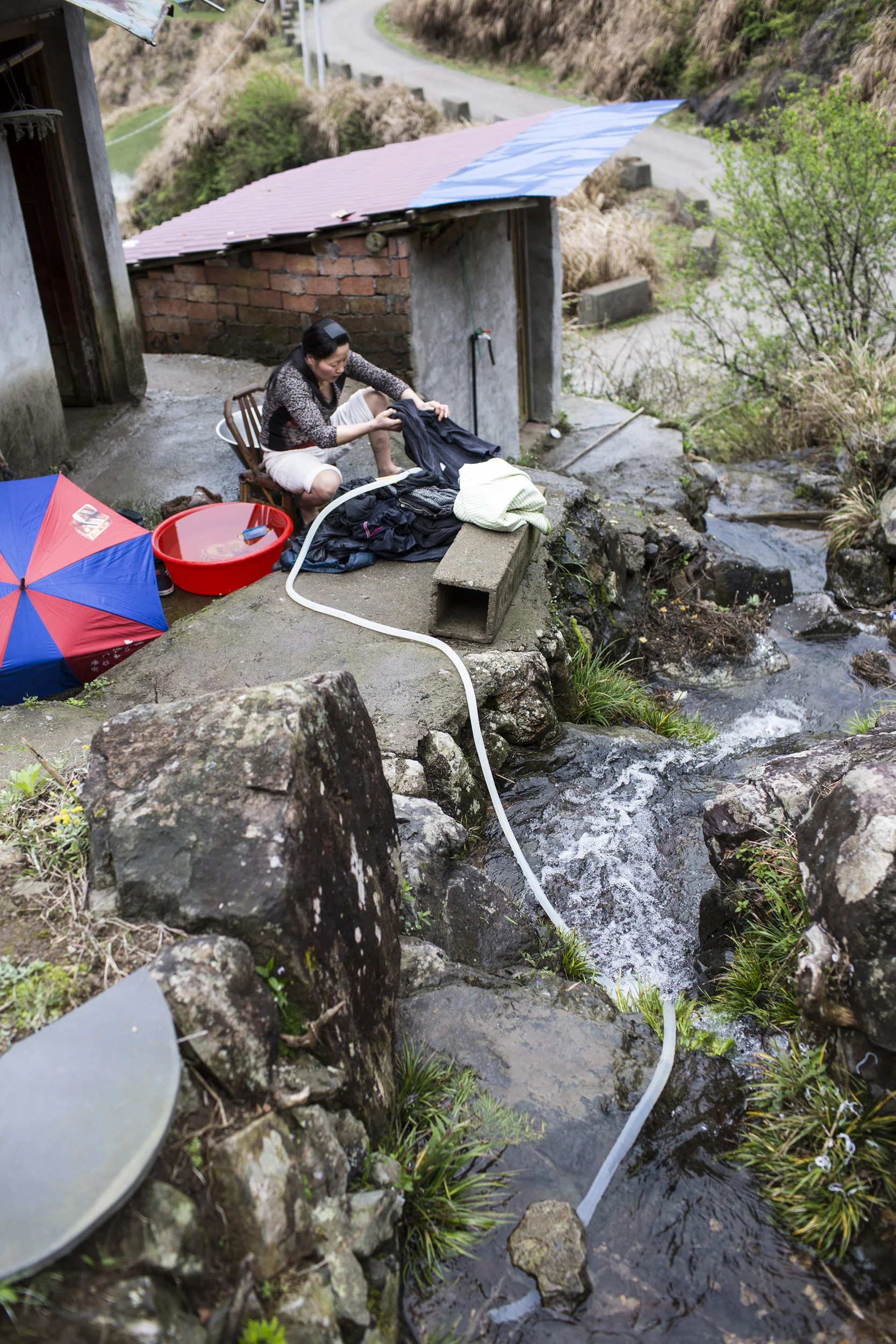  Zhu does laundry by the side of a creek behind the house in rural Mashang Mount, Wenzhou. 
