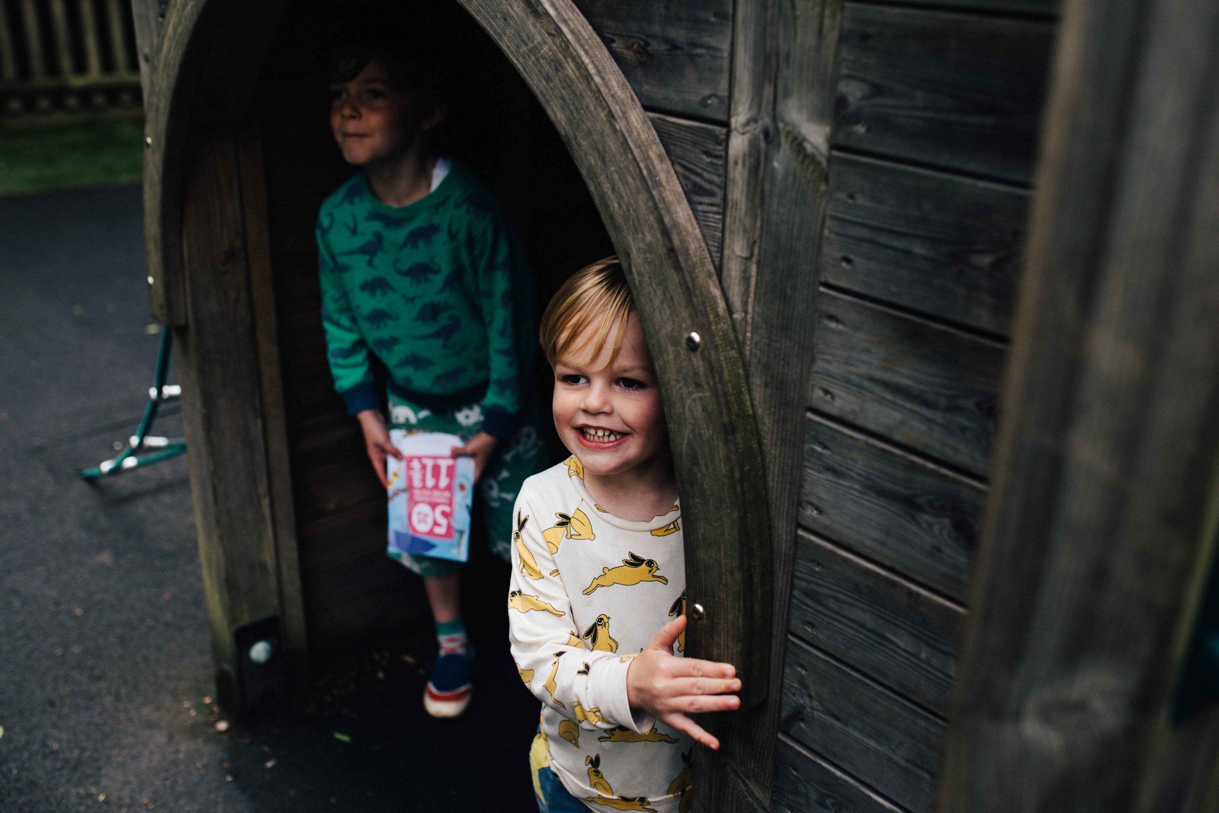 Boys hiding under castle in play area in Claremont Landscape Garden, Surrey, during family photo session